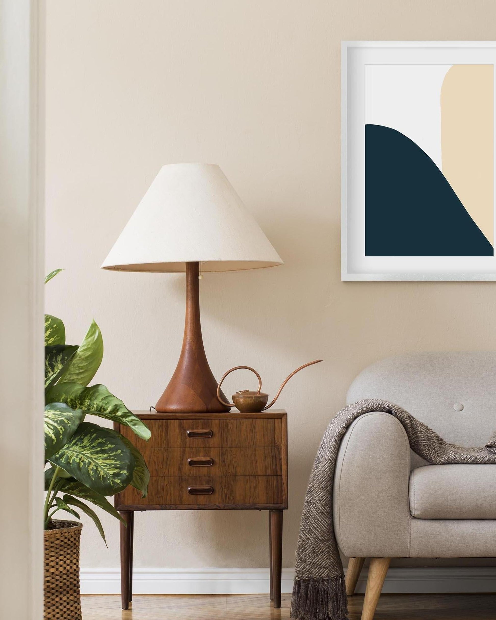 Nest living room with a lamp, plant, and abstract art on the wall.