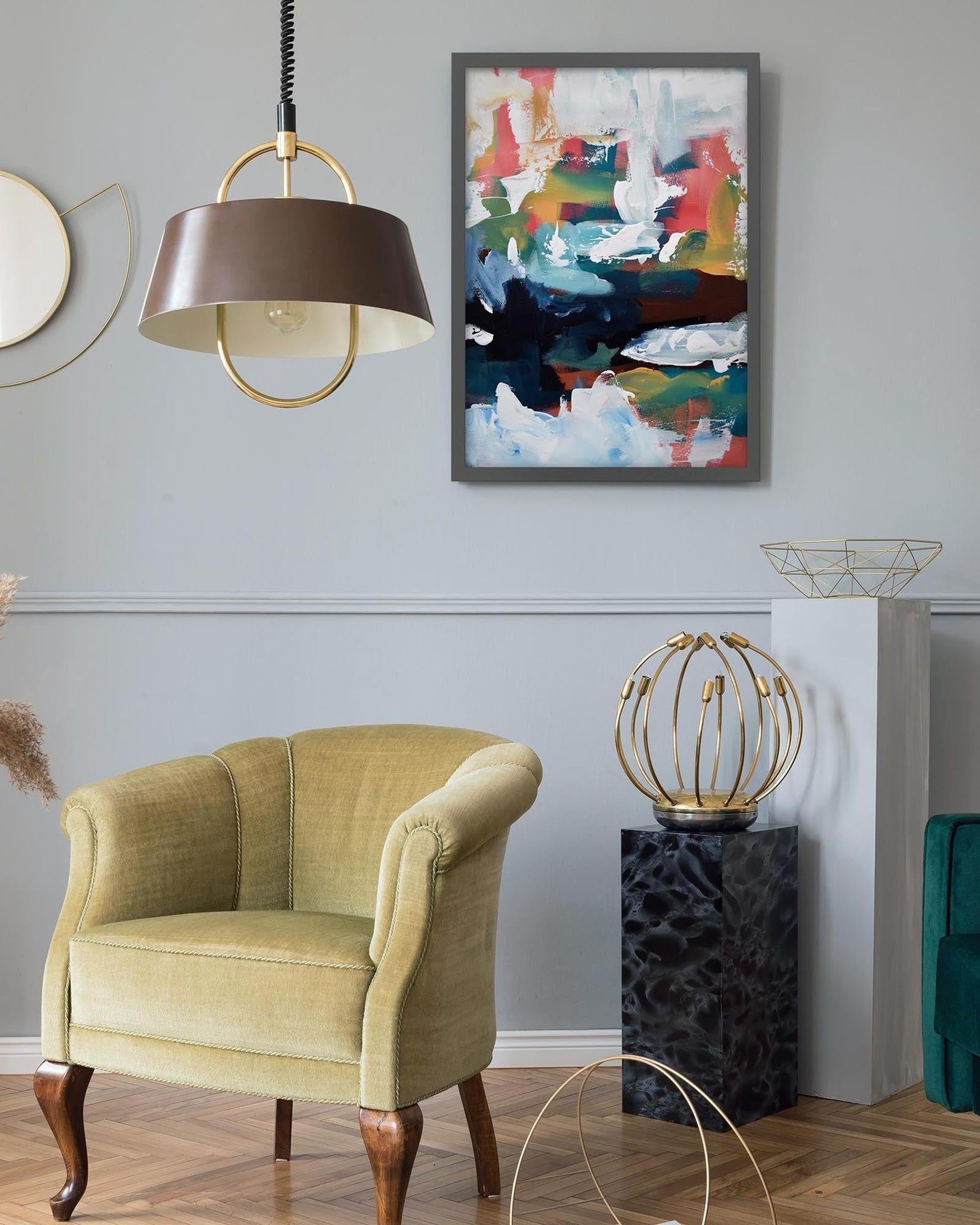 Living room with a green armchair, abstract painting, and decorative lamp.