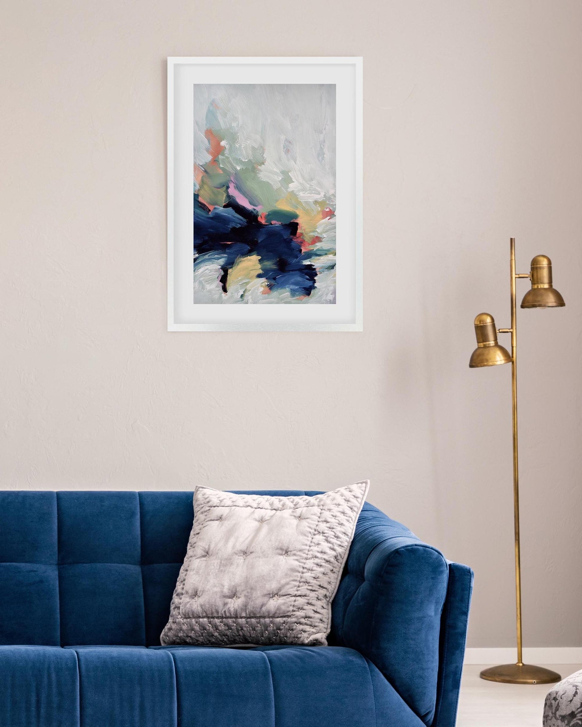 Living room with a blue sofa, abstract art on the wall, and a gold floor lamp.