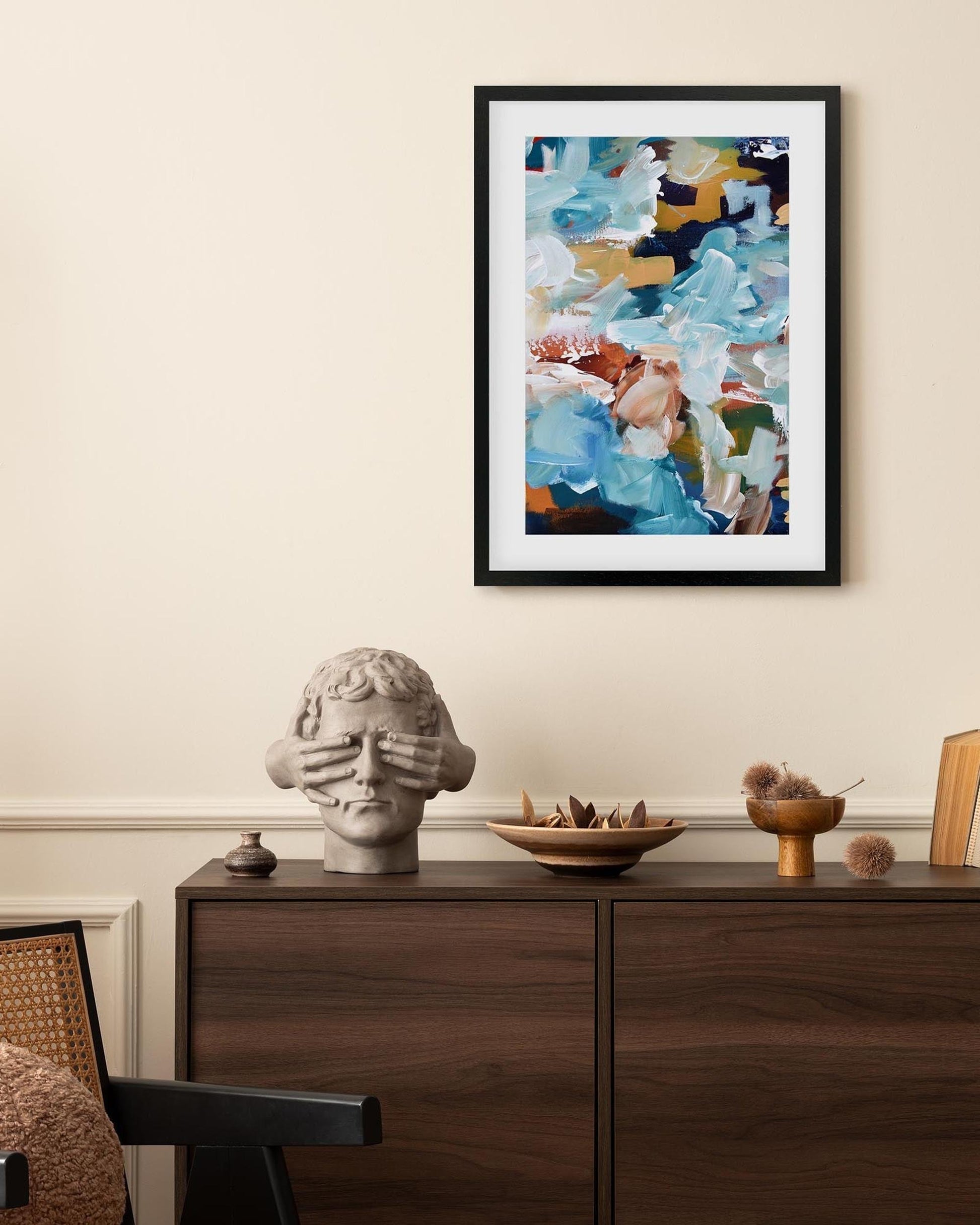 Framed abstract painting on a wall above a wooden console table with decorative items.