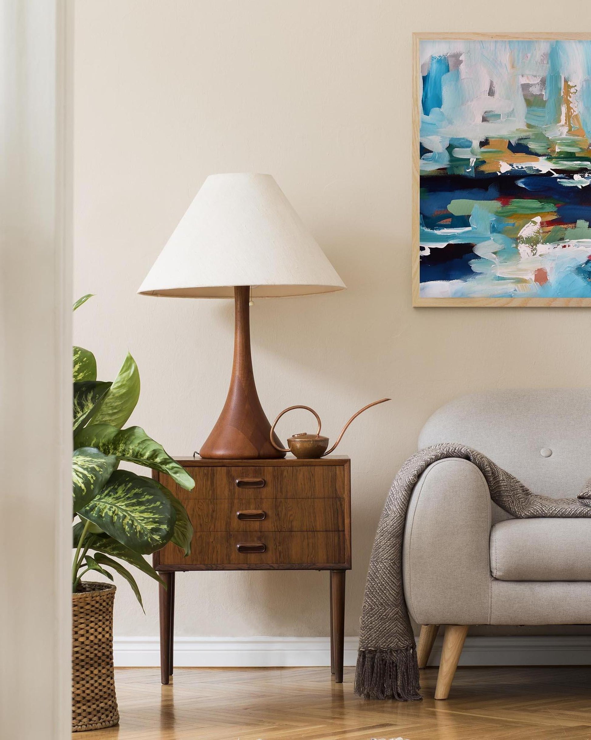Living room with a lamp on a side table, sofa, and abstract painting.