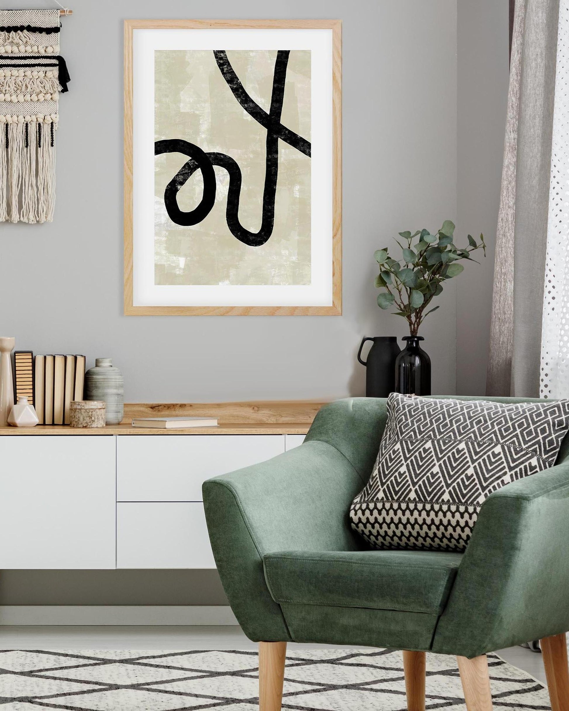 Modern living room with a green armchair, decorative pillow, and framed abstract art on the wall.