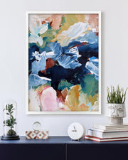 Framed abstract art piece on a wall with decorative items below.