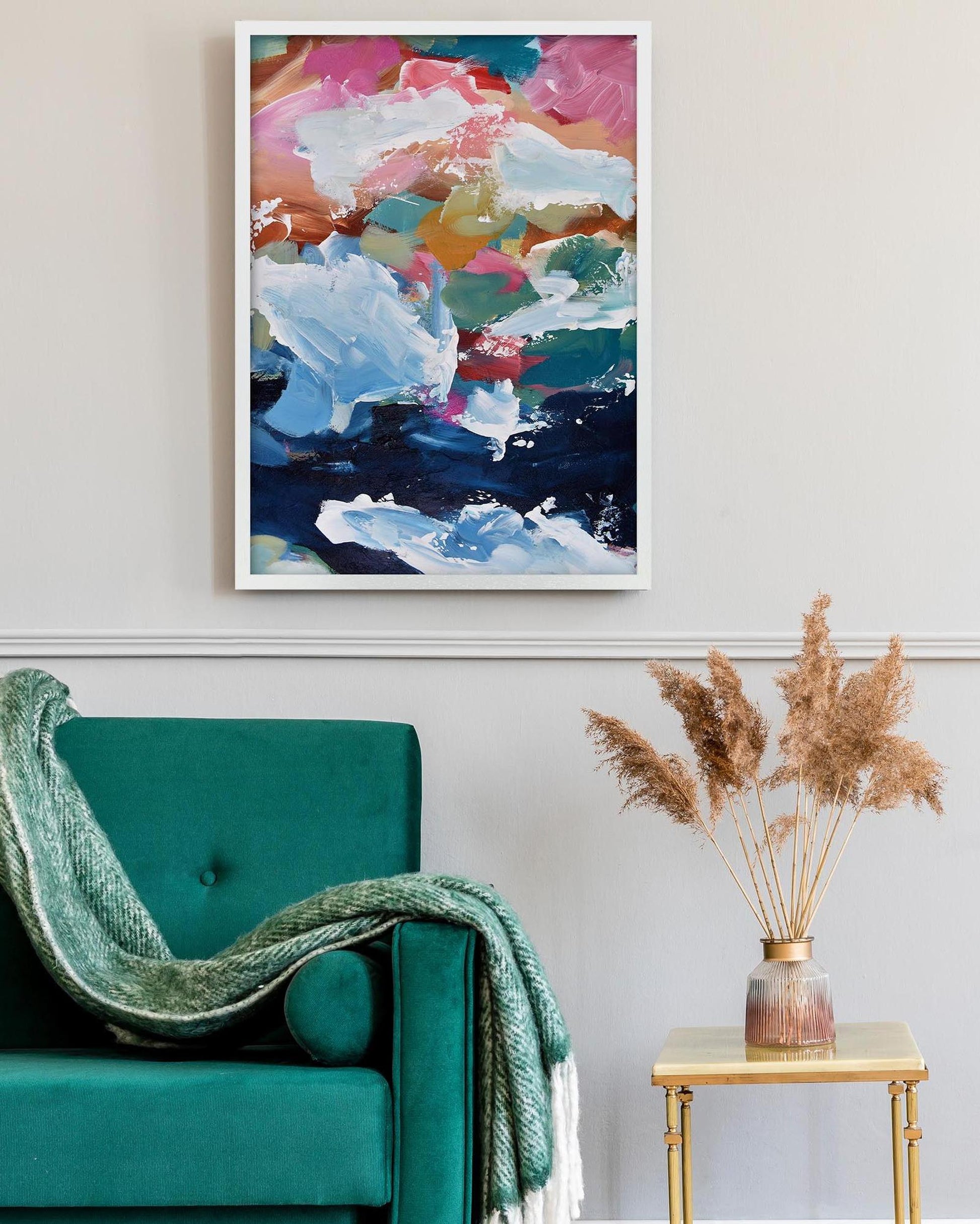 Colorful abstract painting above a teal sofa with a small table and decorative vase.
