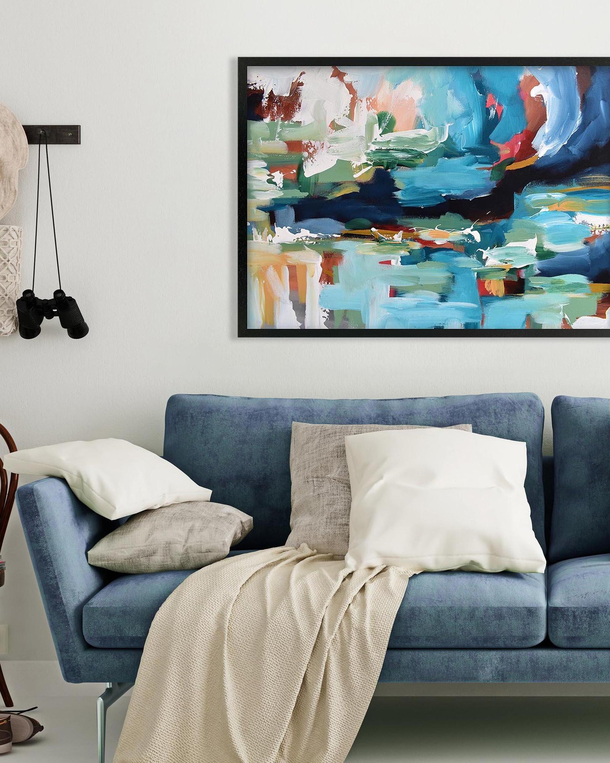 Blue sofa with decorative pillows and a colorful abstract painting on the wall.