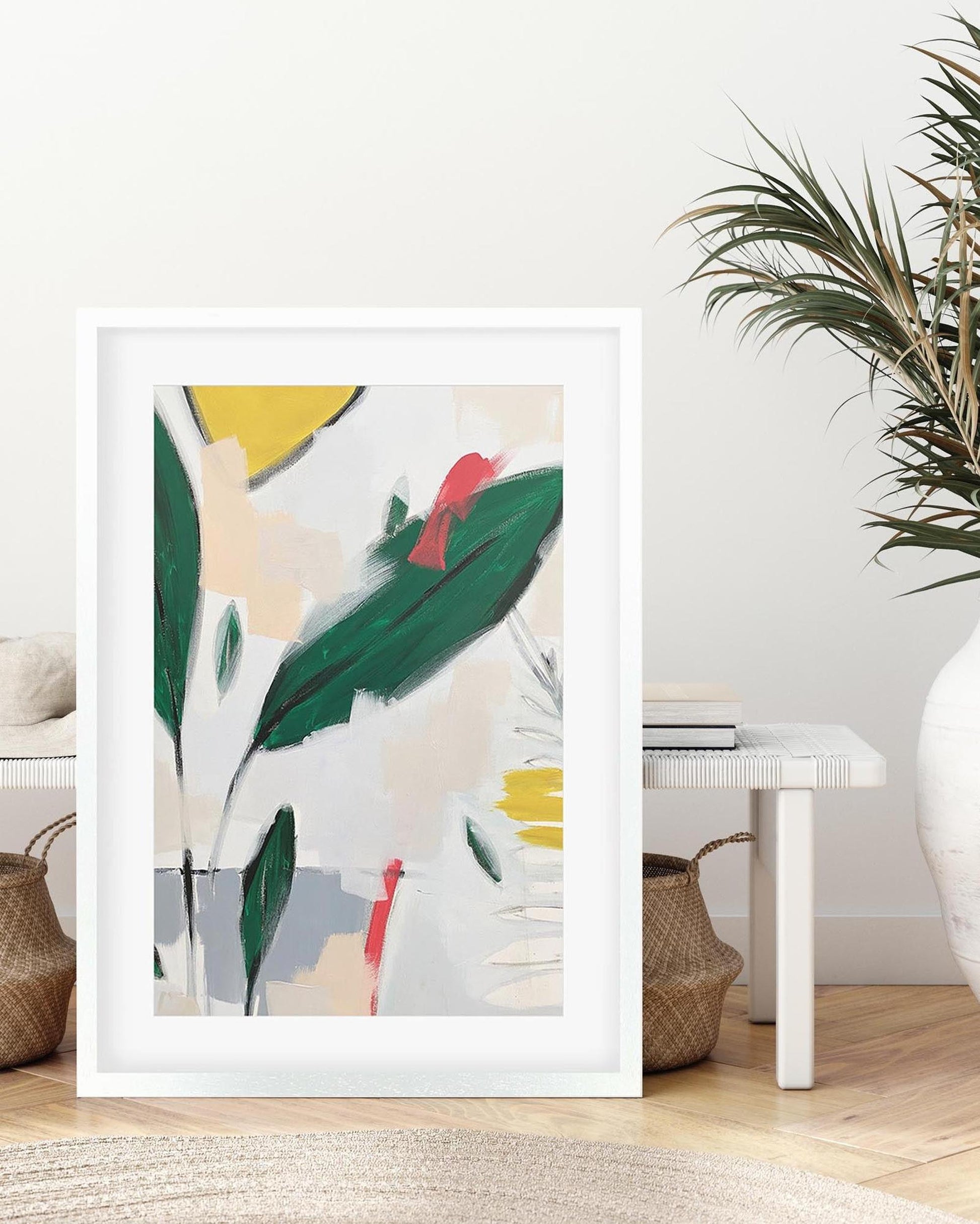 Framed abstract art print with colorful leaves in a room setting.