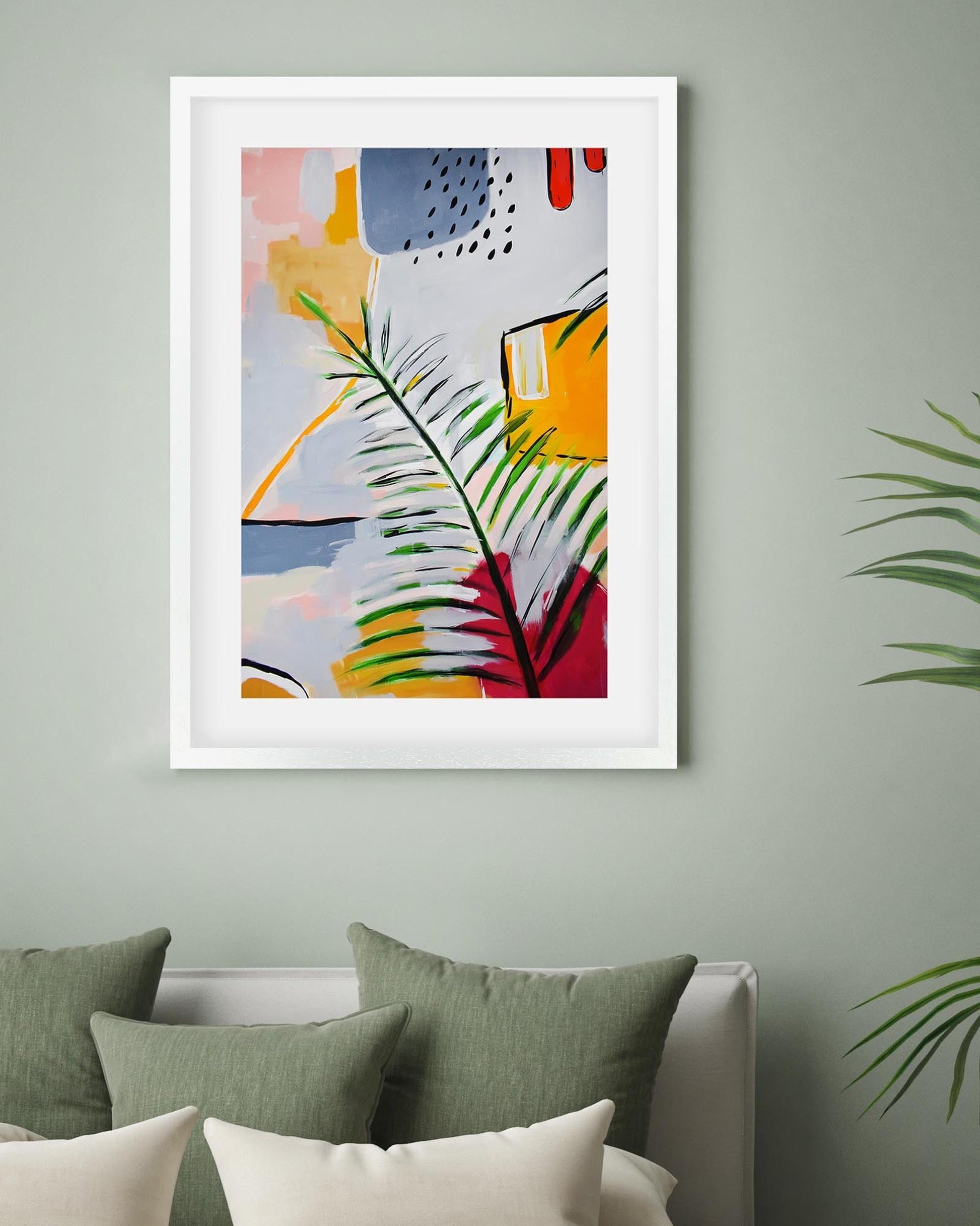 Framed abstract art with green leaves on a wall above a bed with green pillows.