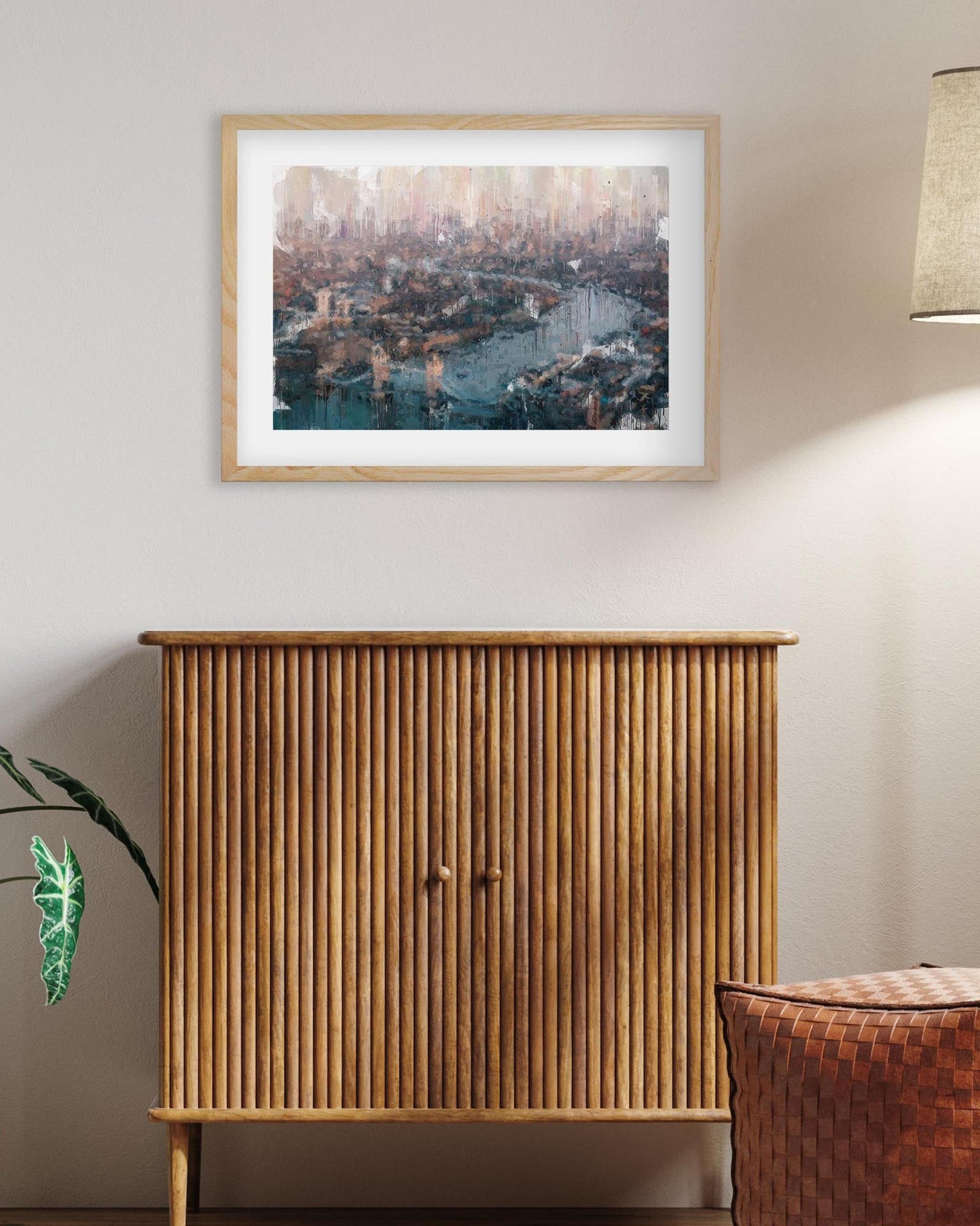 Wooden cabinet with a framed cityscape print on the wall above it.
