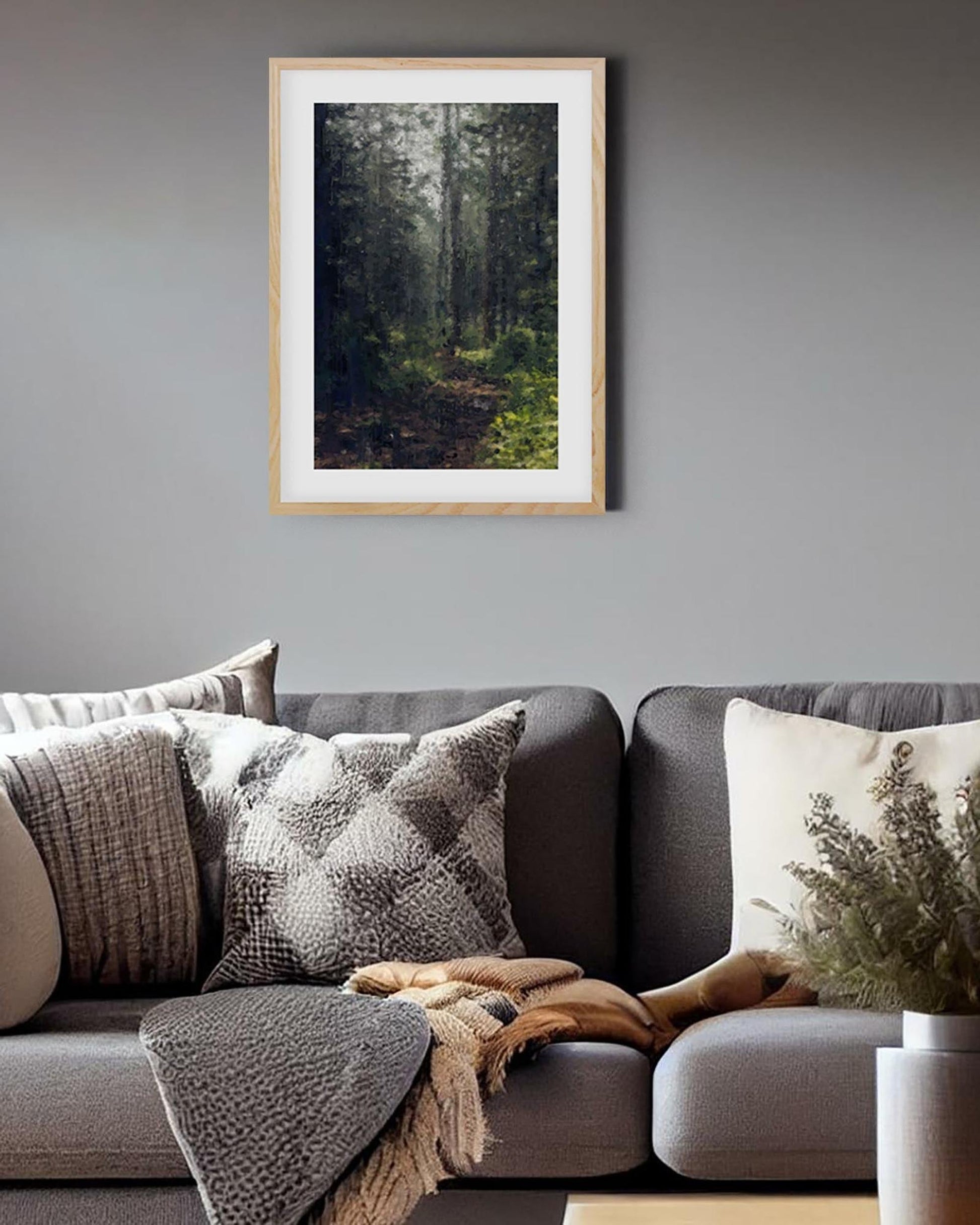 Gray sofa with patterned cushions and a framed forest picture on a gray wall