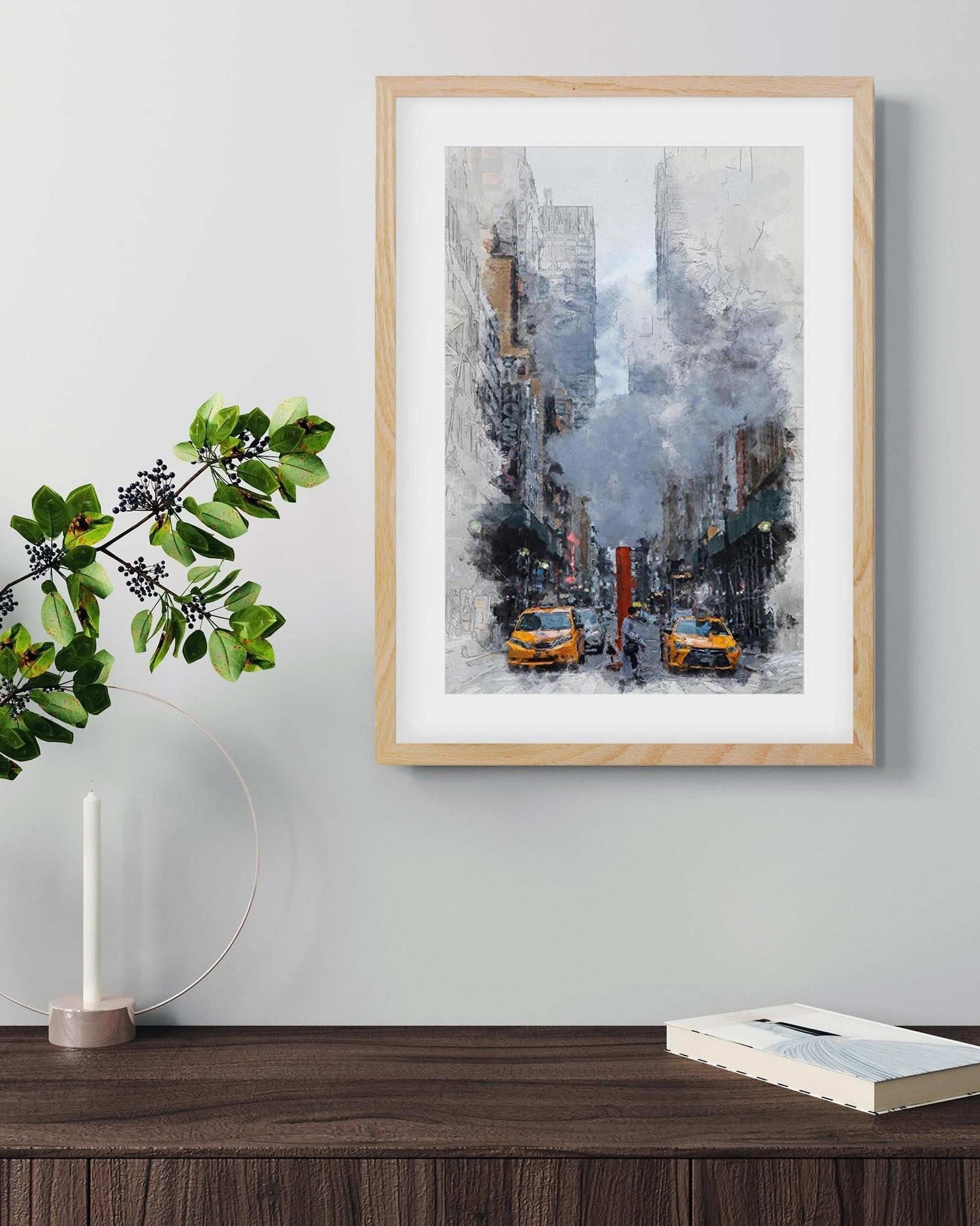 Framed cityscape print with yellow taxis on a wall above a wooden surface with decor items.