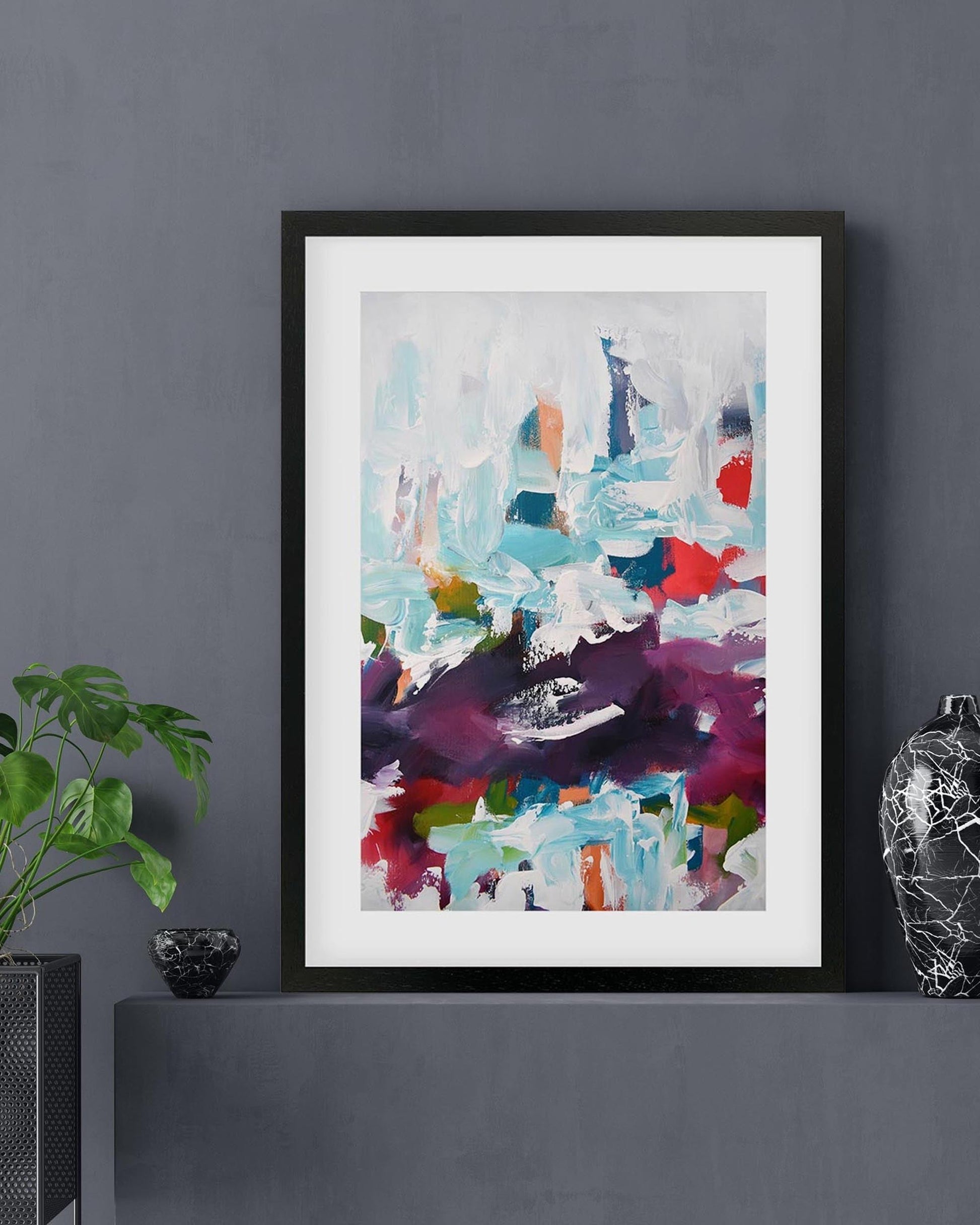Framed abstract art print on a dark wall with decorative elements.