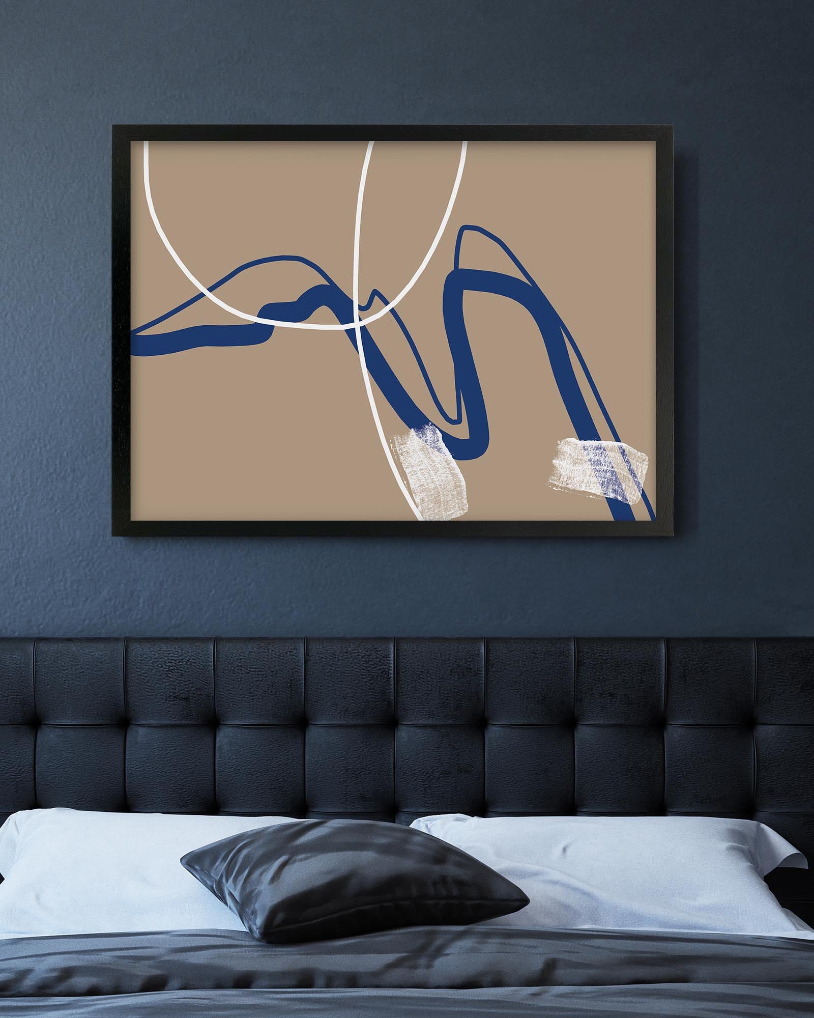 Framed abstract art piece on a wall above a bed with a dark headboard.