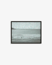 Framed artwork of a beach scene with a person walking on the sand.