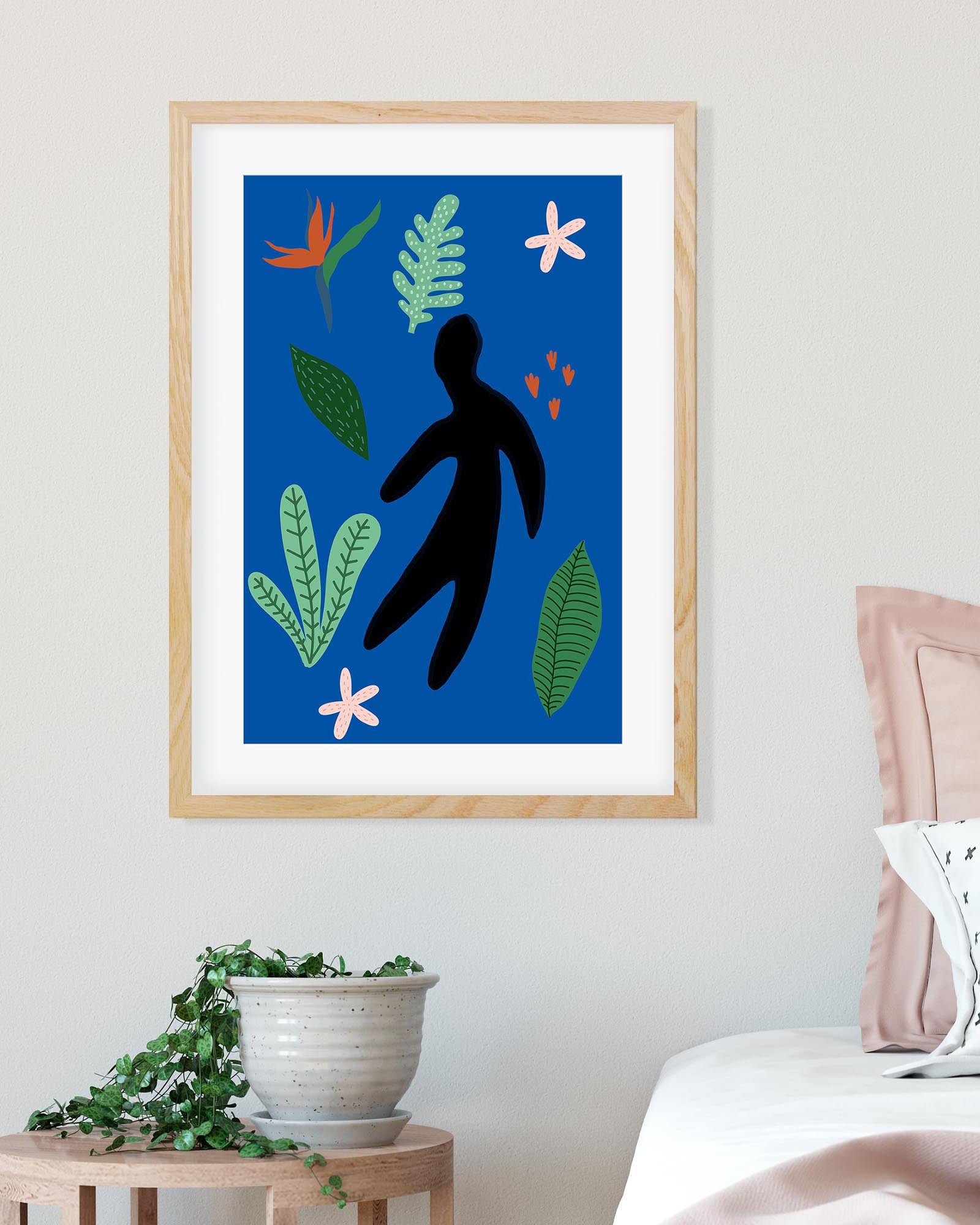 Framed artwork with a blue background, black silhouette, and colorful leaves on a wall.