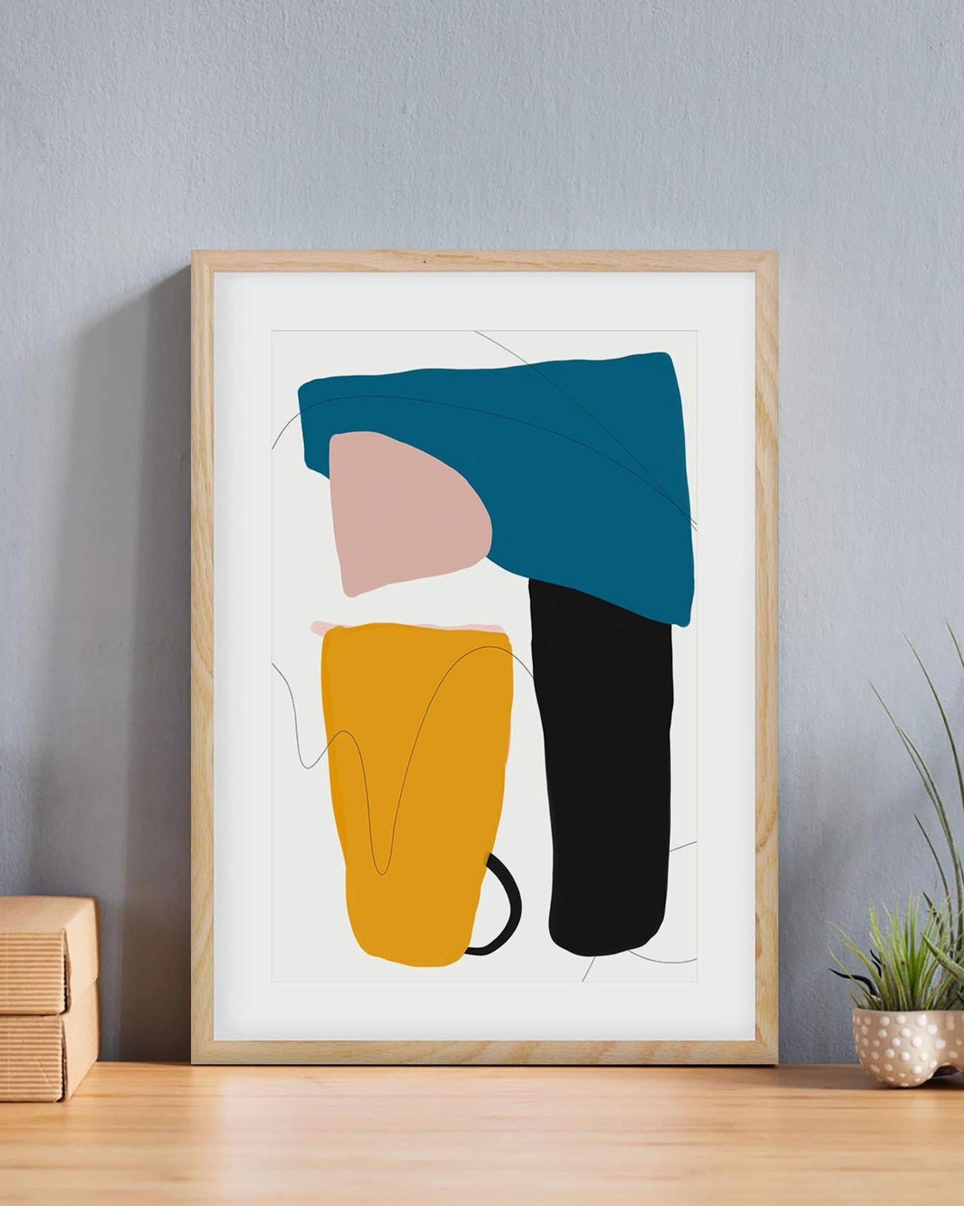 Framed abstract art print with colorful shapes on a gray wall.