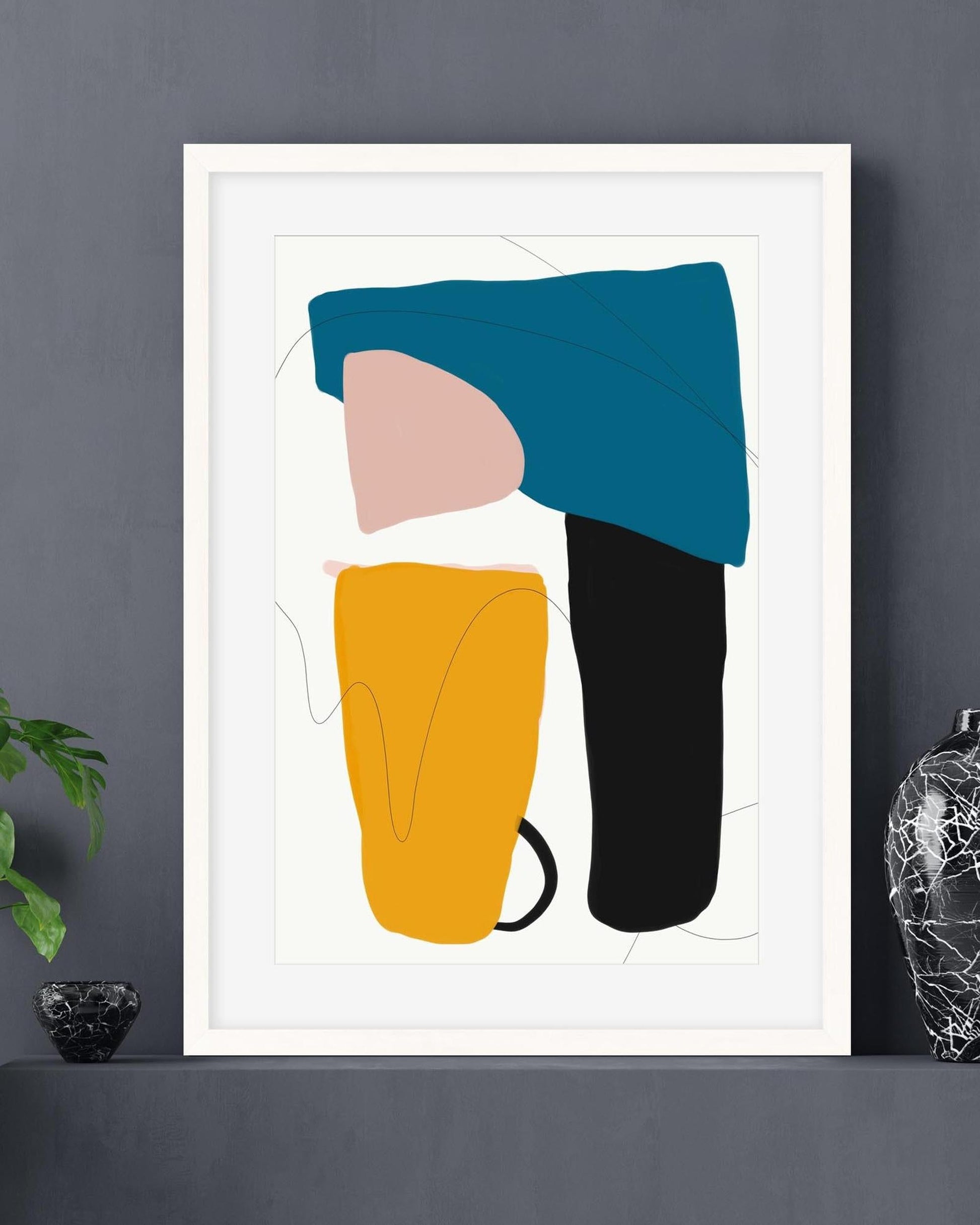 Framed abstract art print with colorful shapes on a gray wall.