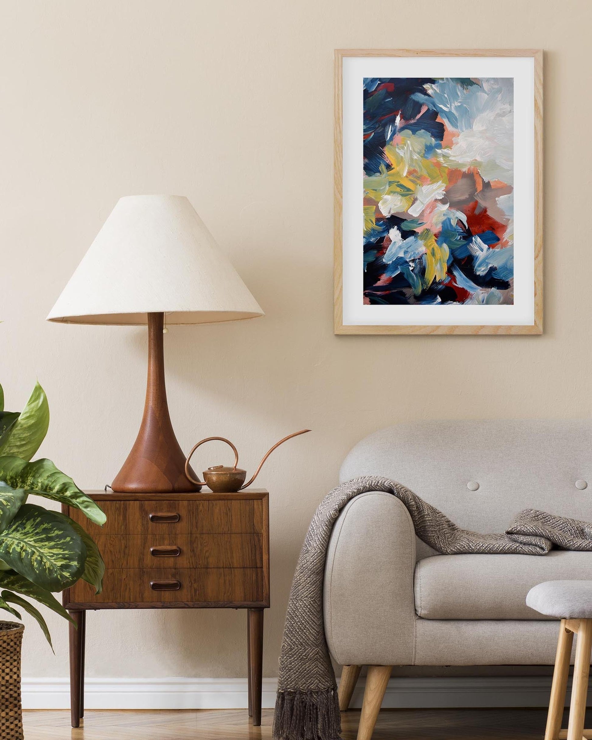 Living room with a lamp, side table, sofa, and abstract art on the wall.