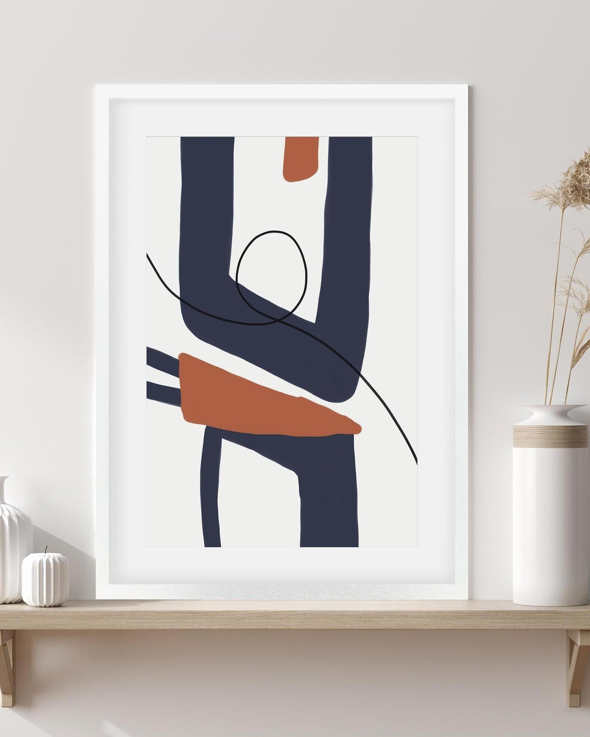 Abstract art print in a white frame on a wall with minimal decor.