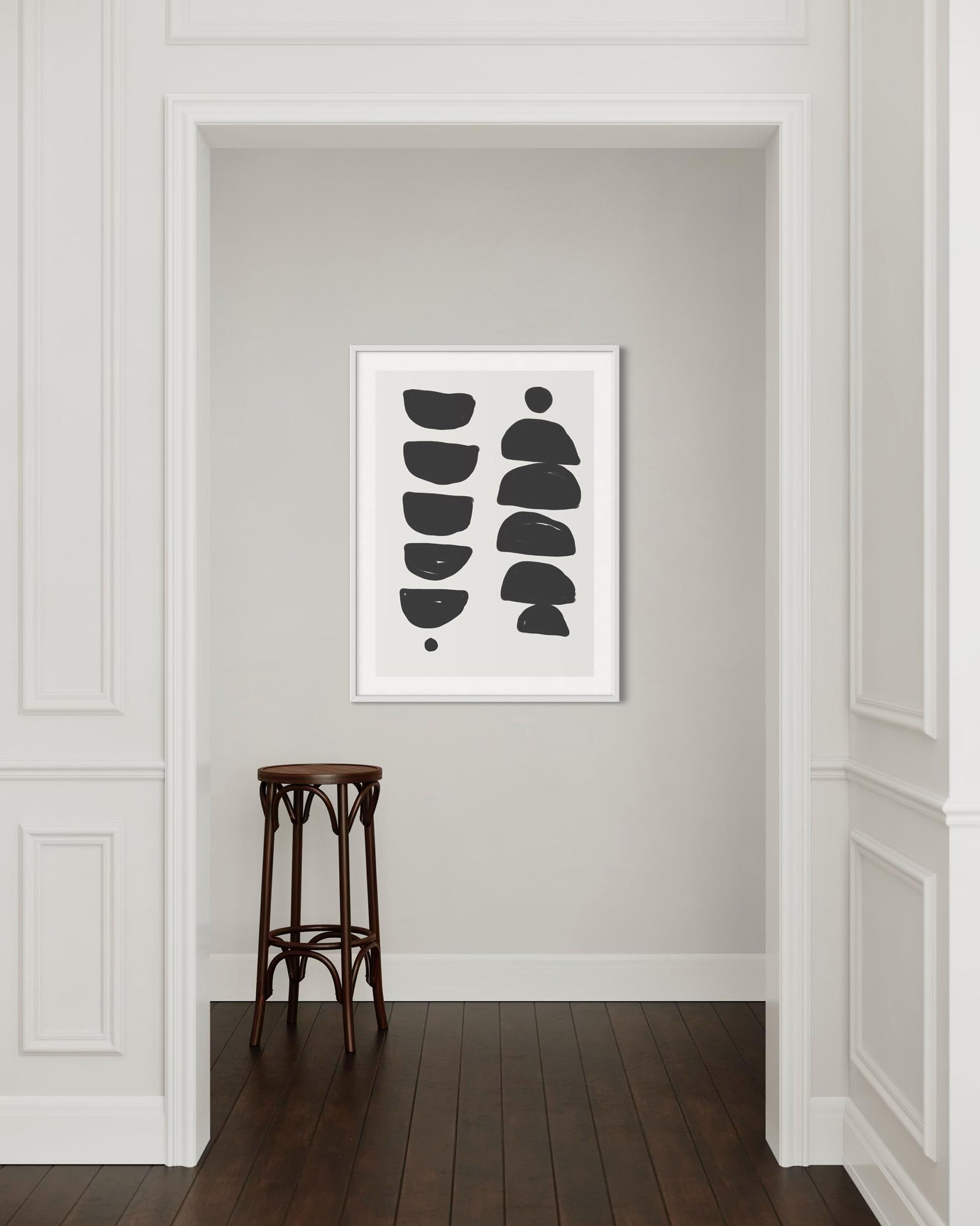 Framed abstract art on a wall with a wooden stool in the foreground