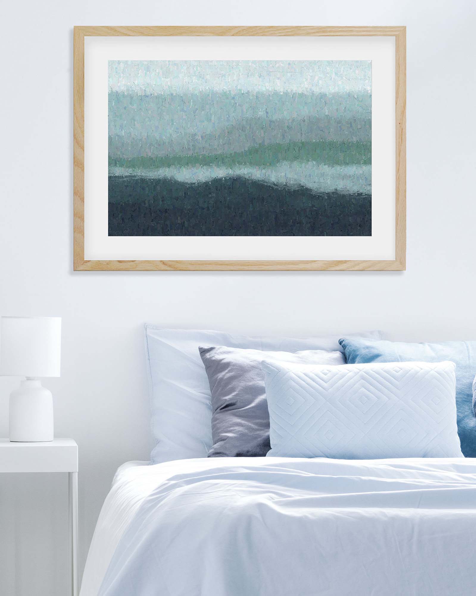 Framed abstract art above a bed with white bedding and blue pillows.