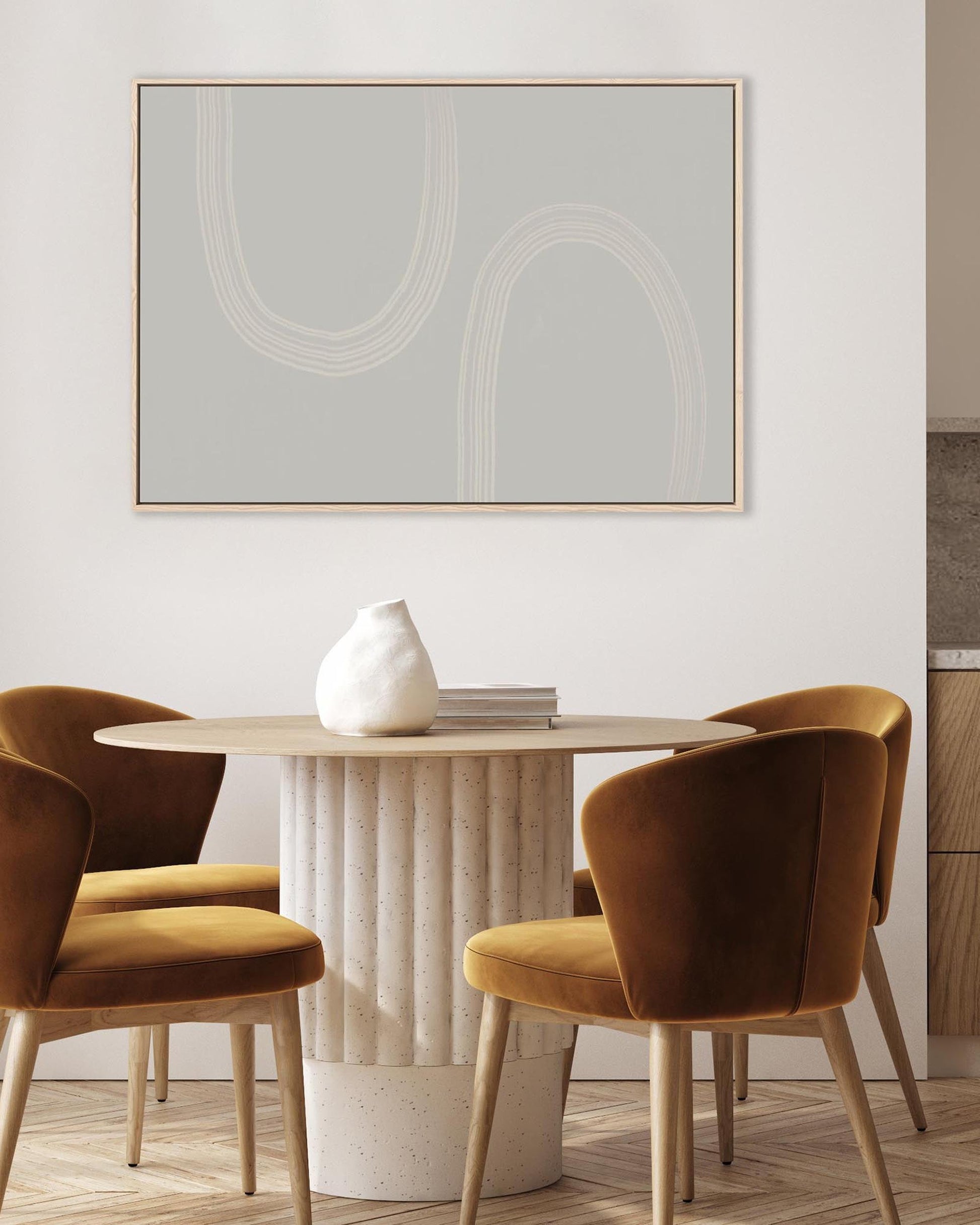 Dining area with round table and brown chairs, featuring a abstract art piece on the wall.