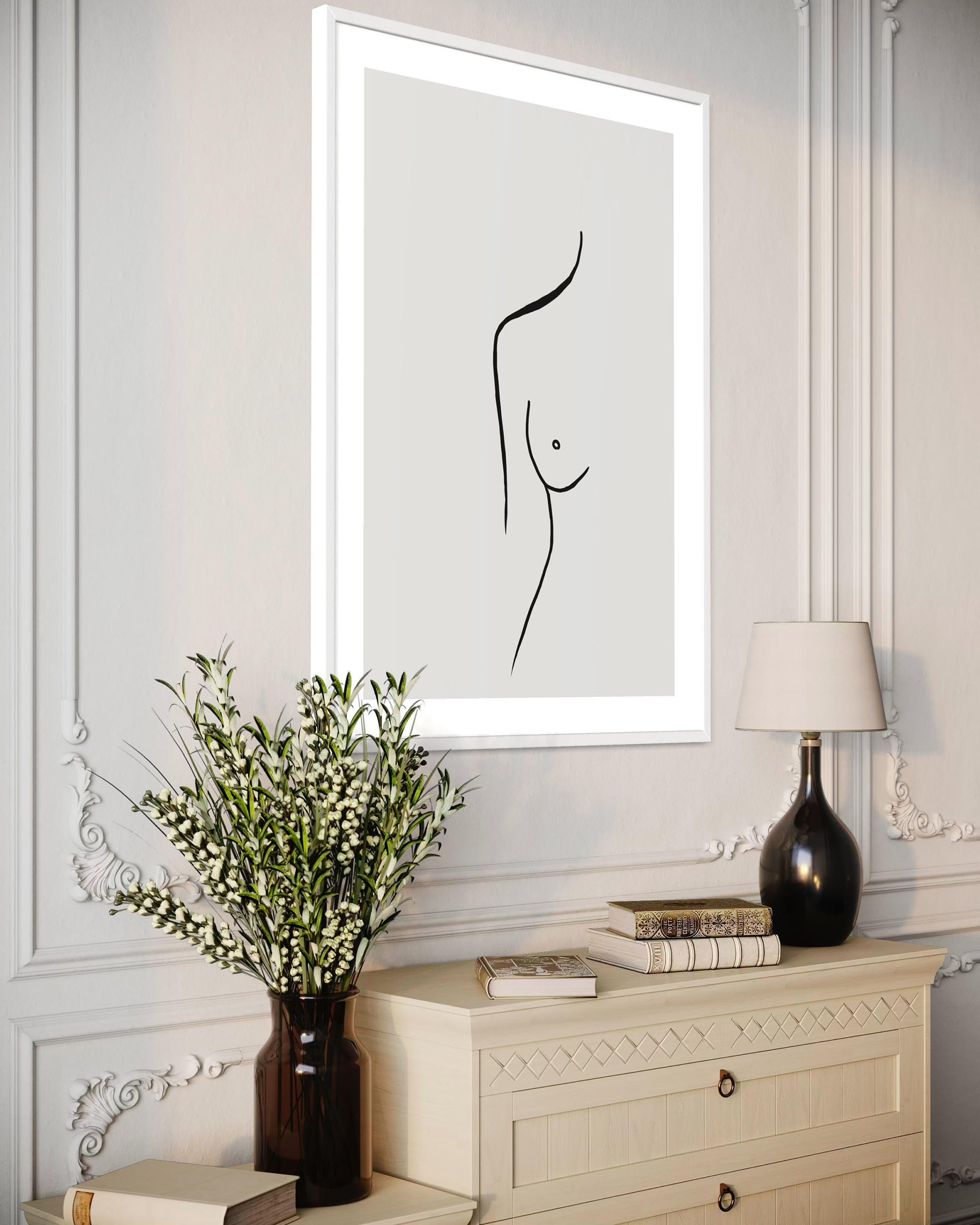 Framed abstract art of a nude figure on a wall above a dresser with decorative items.