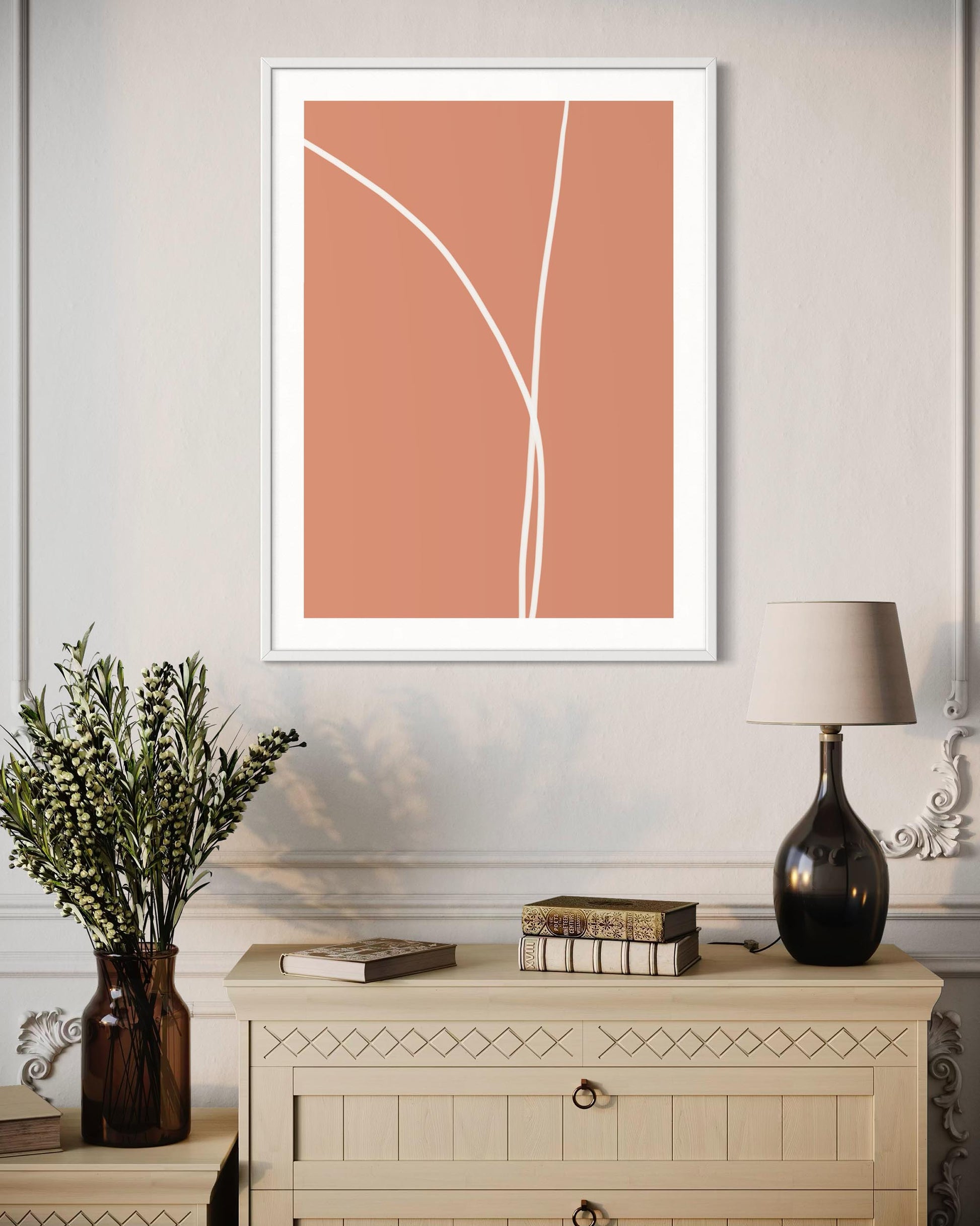 Framed abstract art on a wall above a cabinet with decorative items.