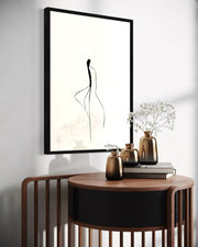 Modern interior with a round wooden table, decorative vases, and framed abstract art on a white wall.