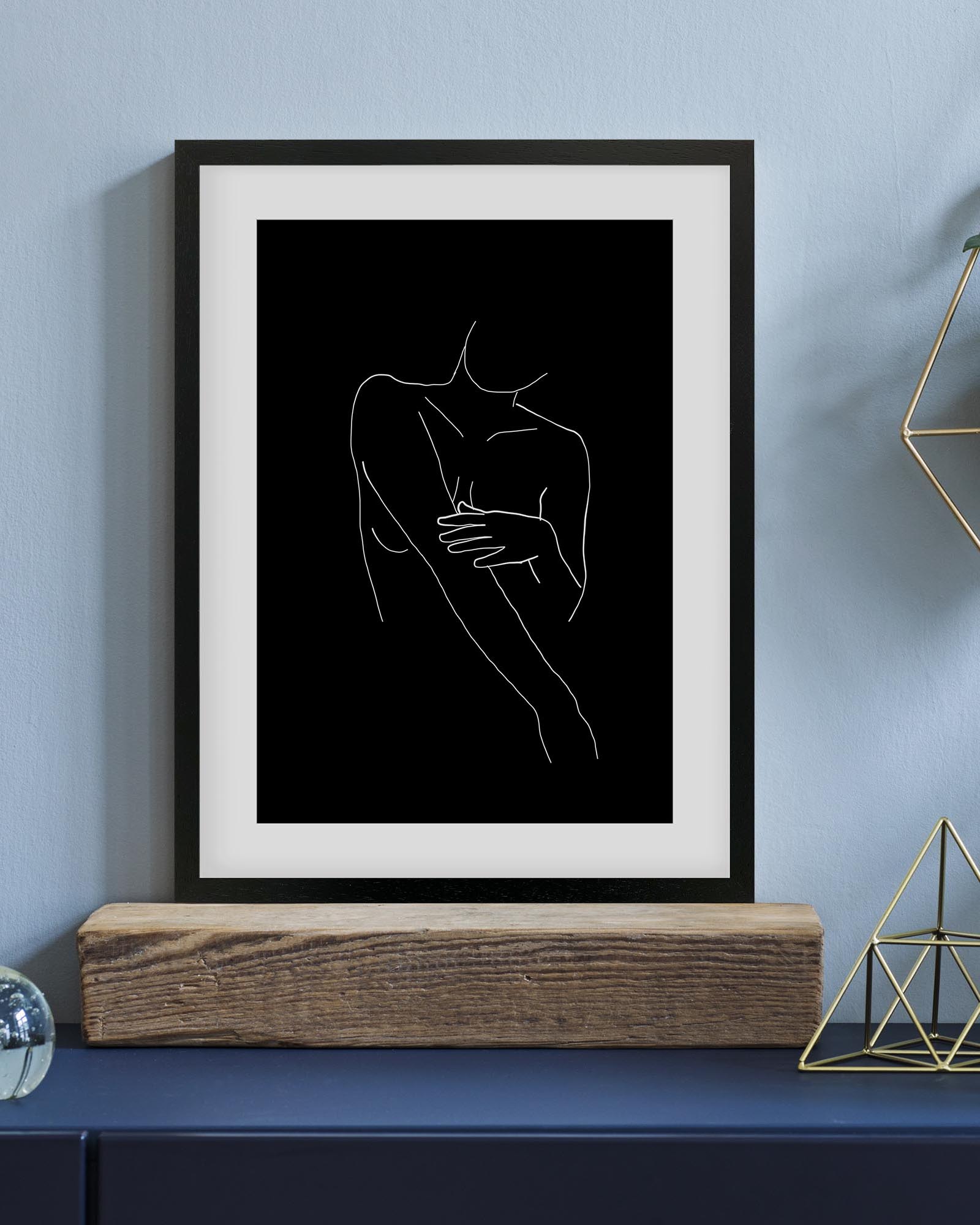 Framed line art of a couple embracing on a shelf against a blue wall.