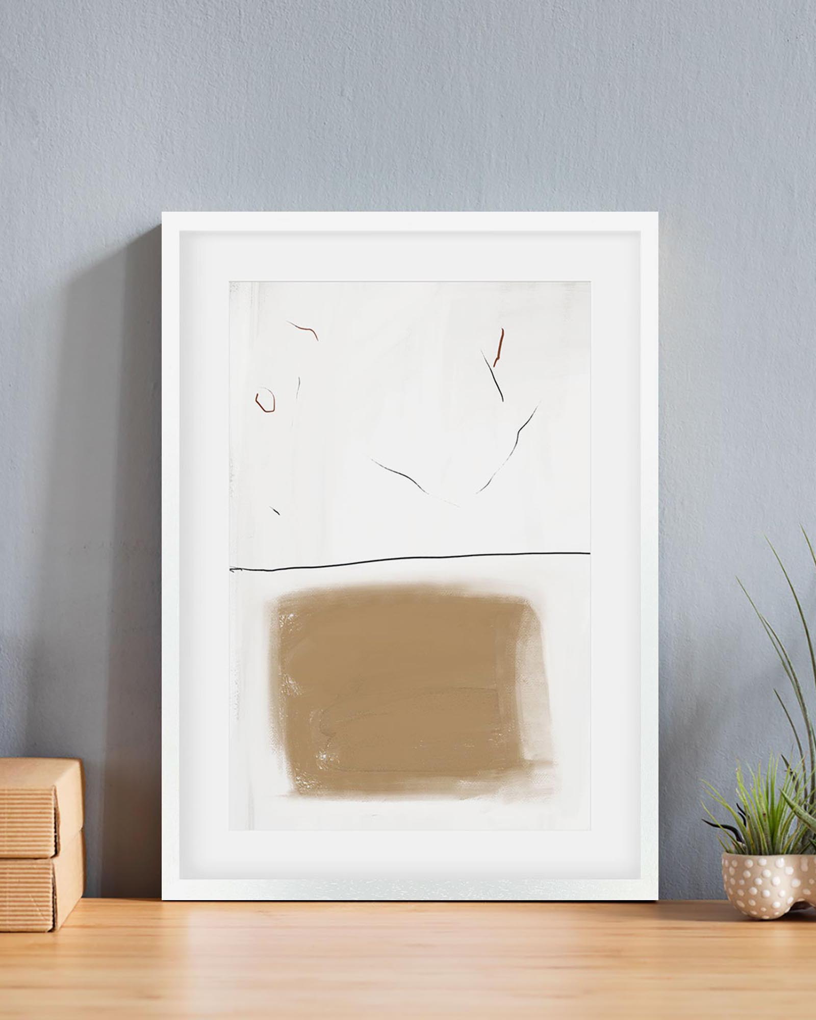 Abstract art piece in a white frame on a wall with a plant and wooden box below.