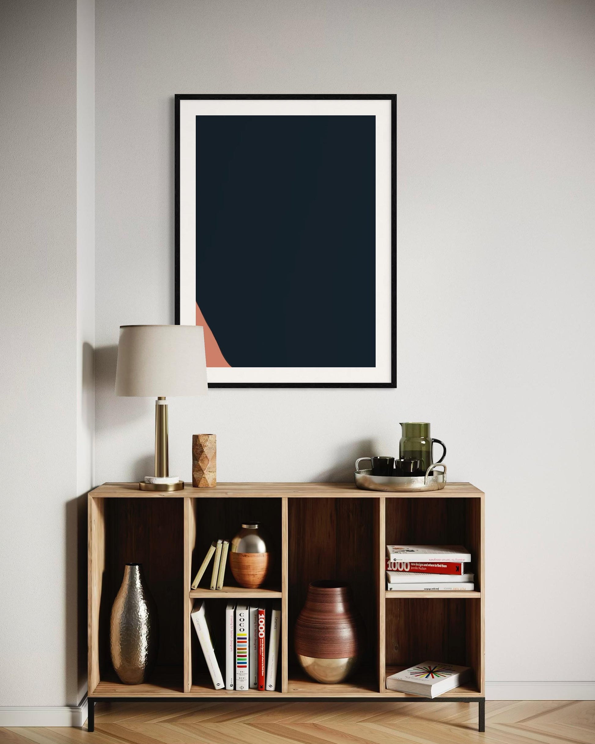 Framed abstract art piece on a wall above a wooden shelf with decorative items.