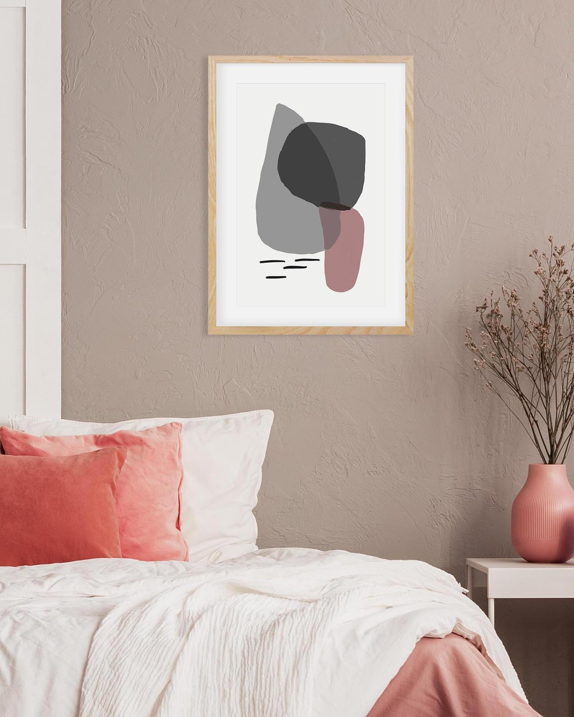Framed abstract art on a wall above a bed with pink and white bedding.