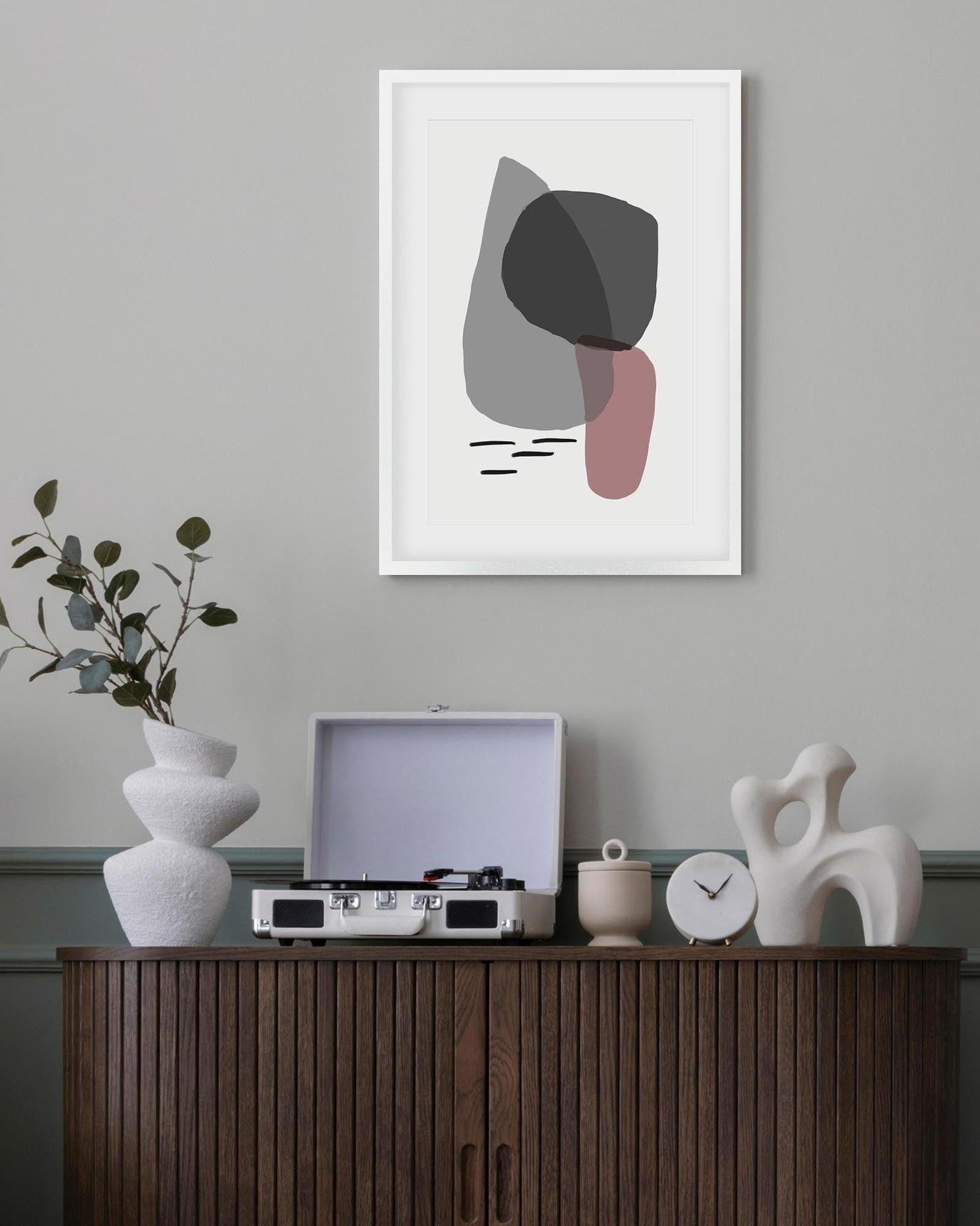 Abstract art print on a wall above a wooden cabinet with decorative items.