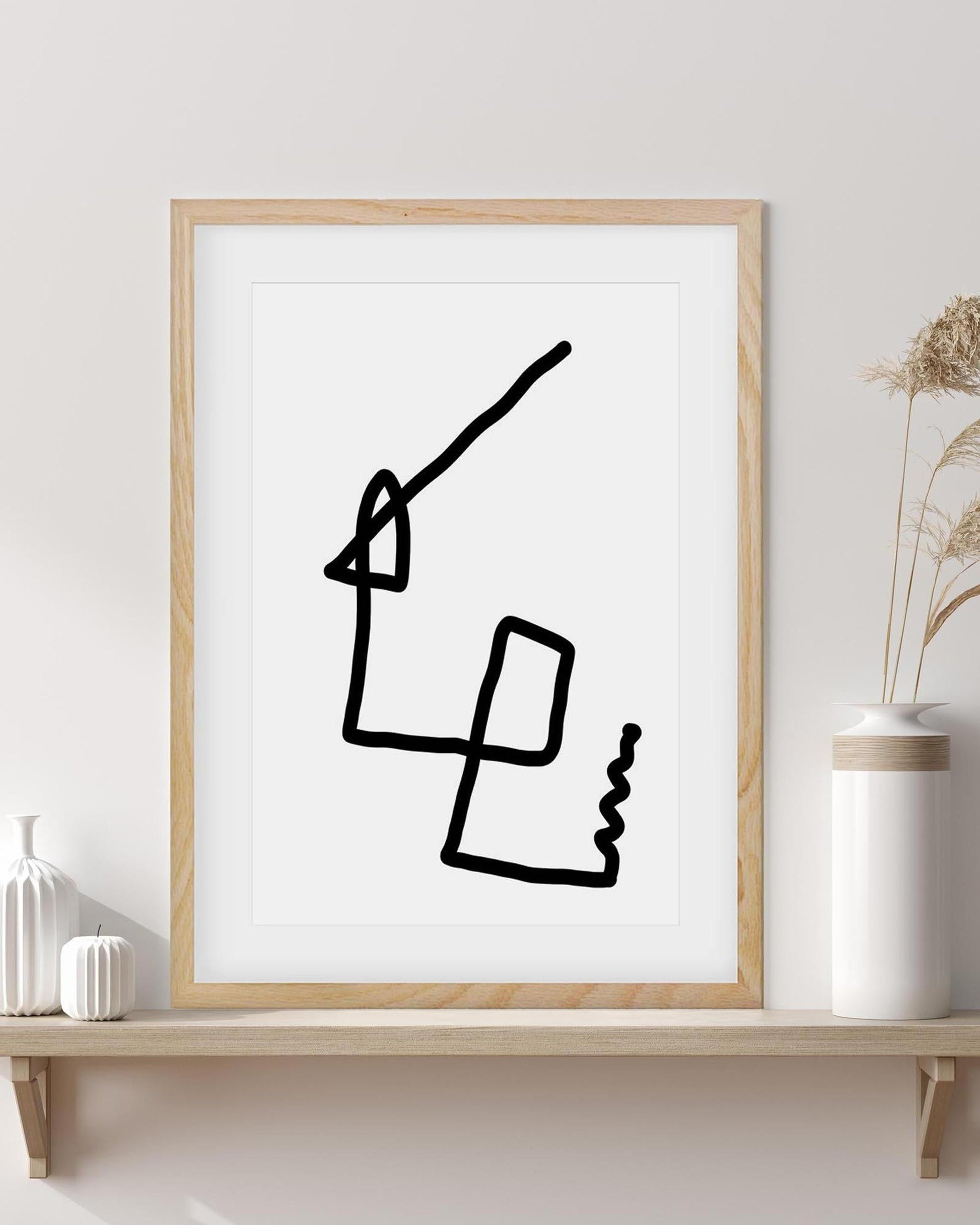 Framed abstract black line art on a white wall with decorative vases.
