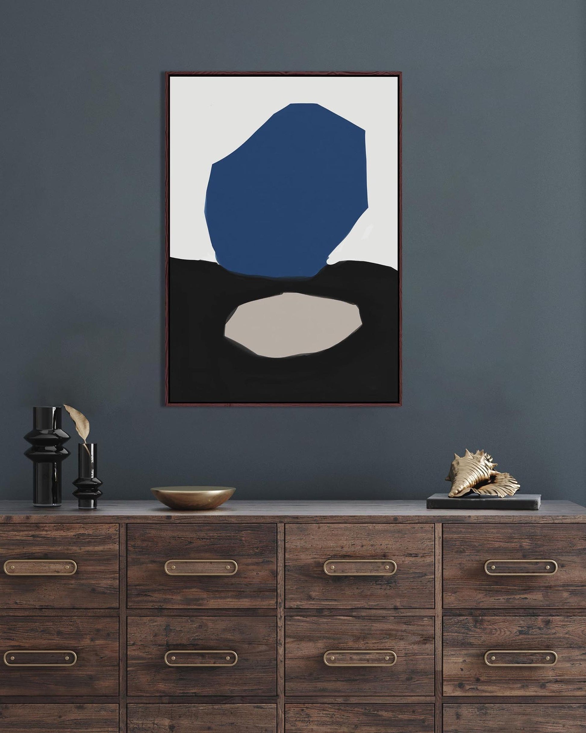 Abstract art print on a wall above a wooden cabinet with decorative items.