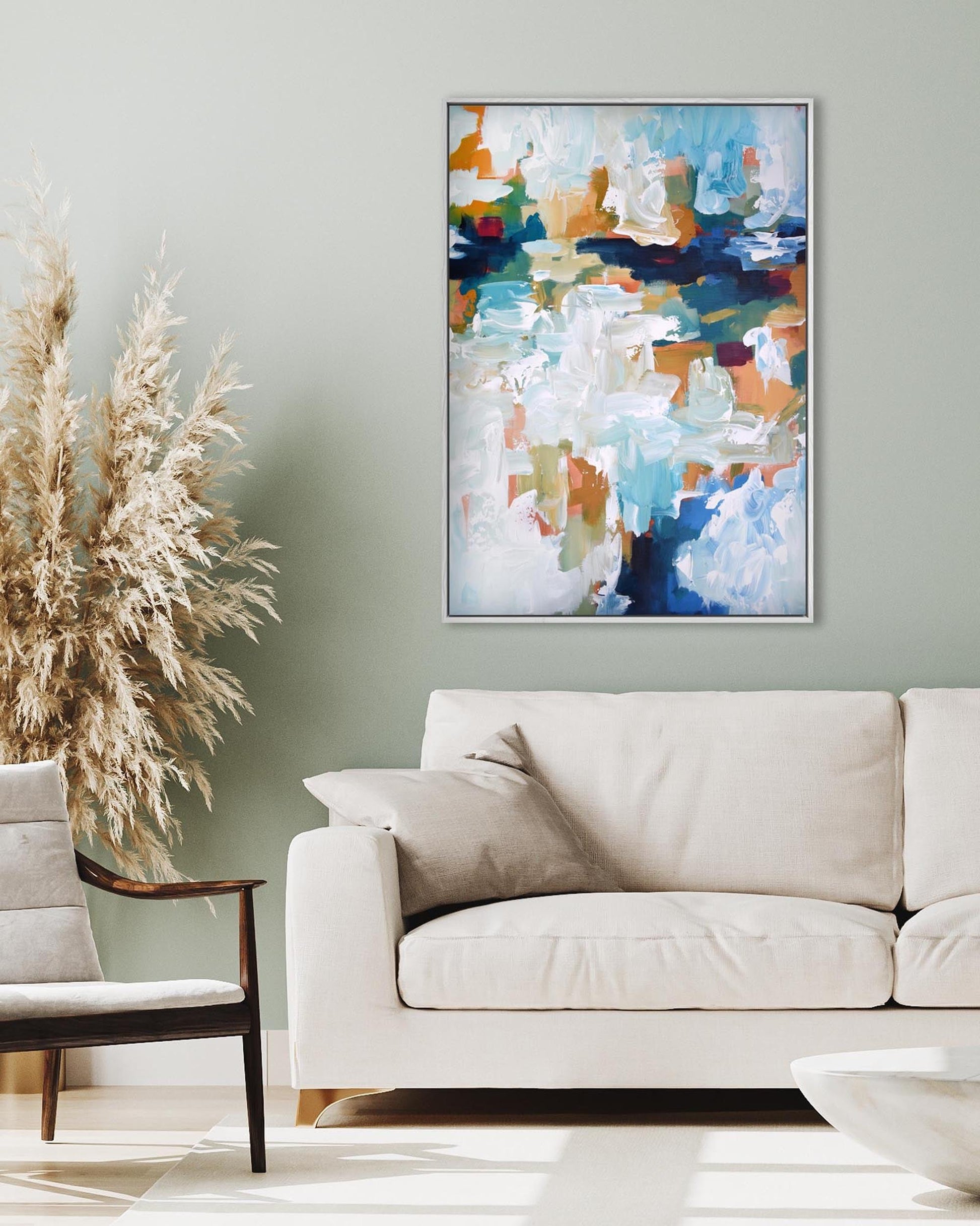 Abstract painting on a wall above a beige sofa in a living room.