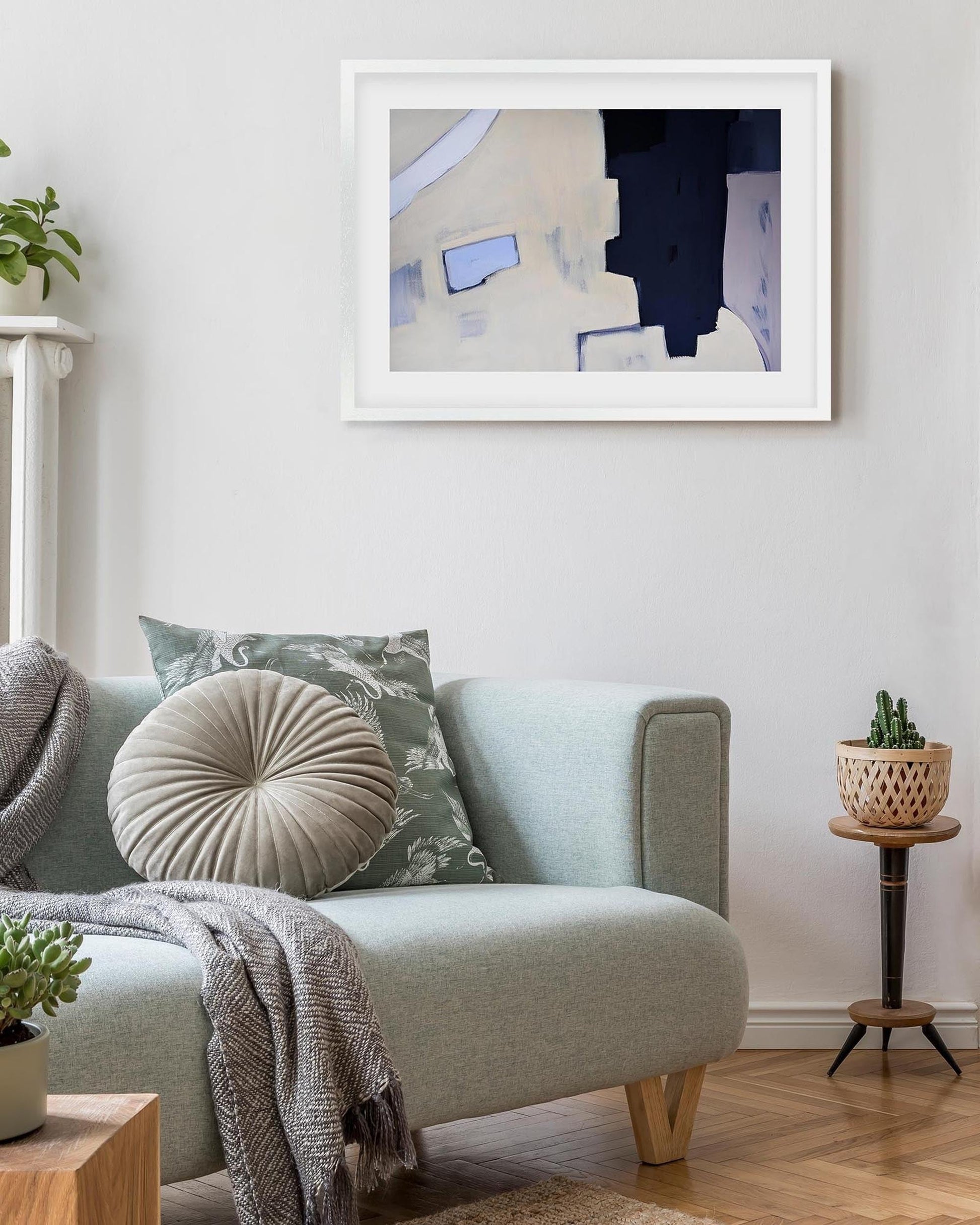 Living room with a light gray sofa, decorative pillows, and a framed abstract painting on the wall.