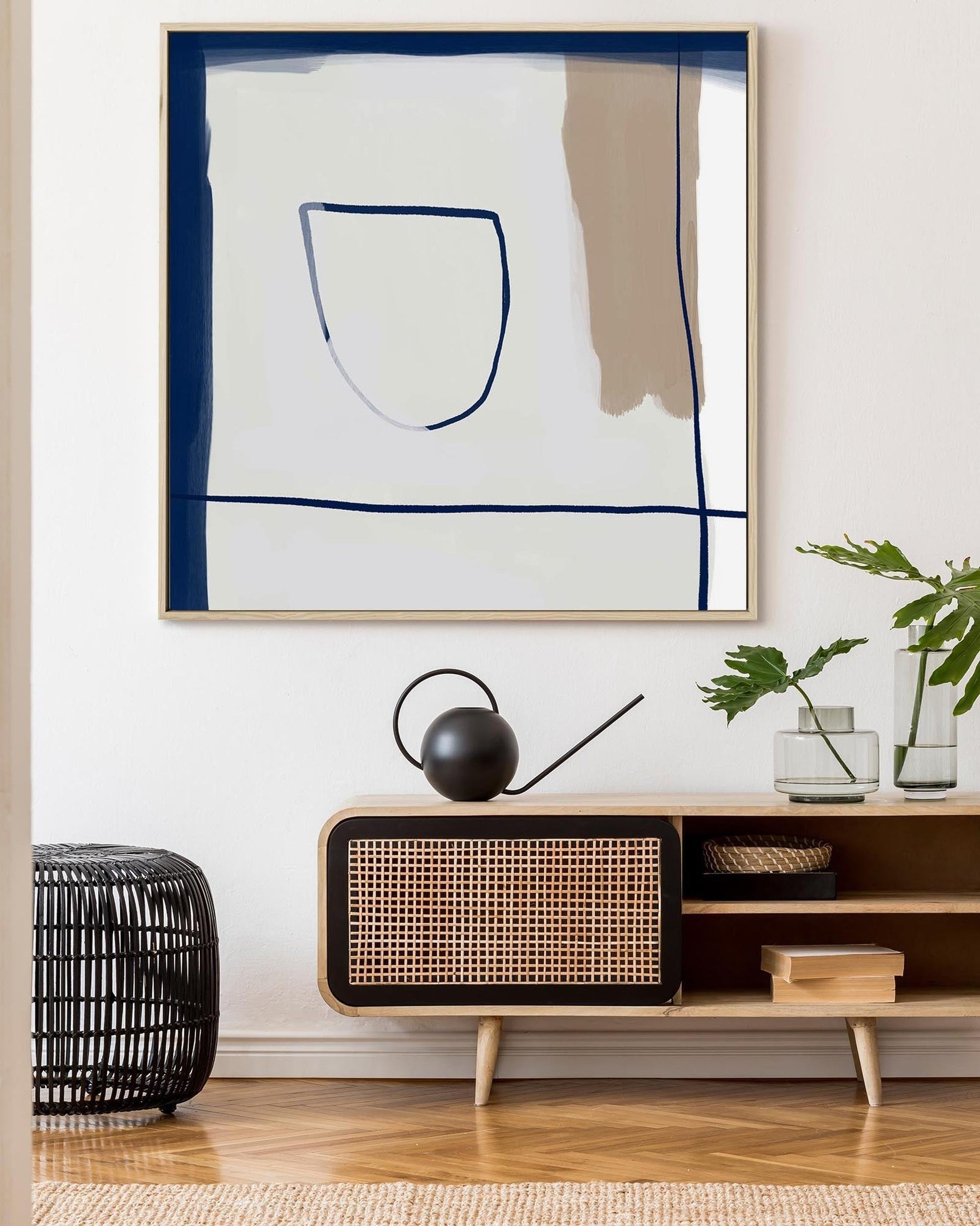 Modern interior with abstract art, wicker cabinet, and plants.