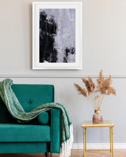 Teal armchair with a green blanket, abstract art on the wall, and a small table with dried plants.