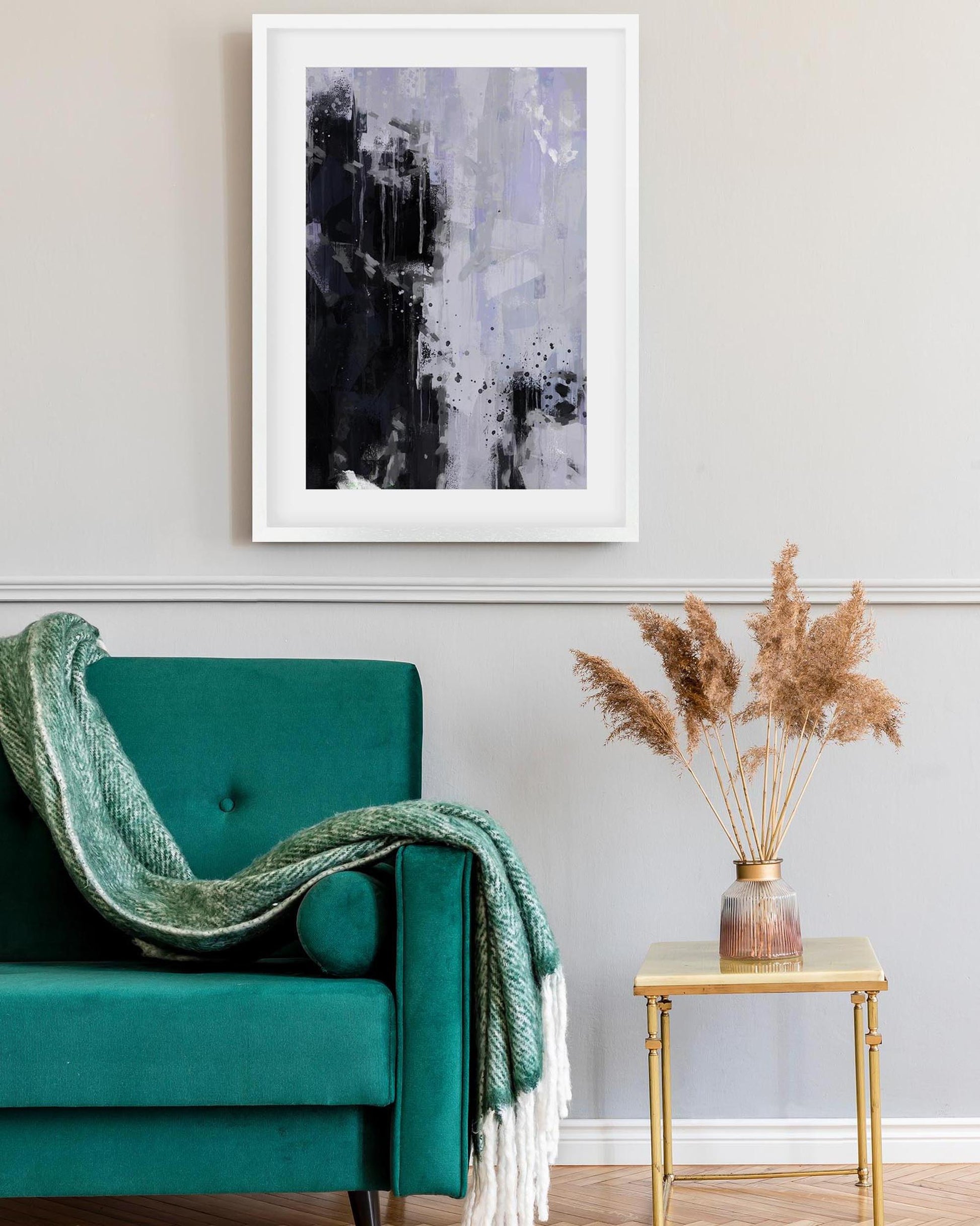 Teal armchair with a green blanket, abstract art on the wall, and a small table with dried plants.