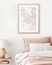 Framed abstract artwork above a bed with pink and white bedding.