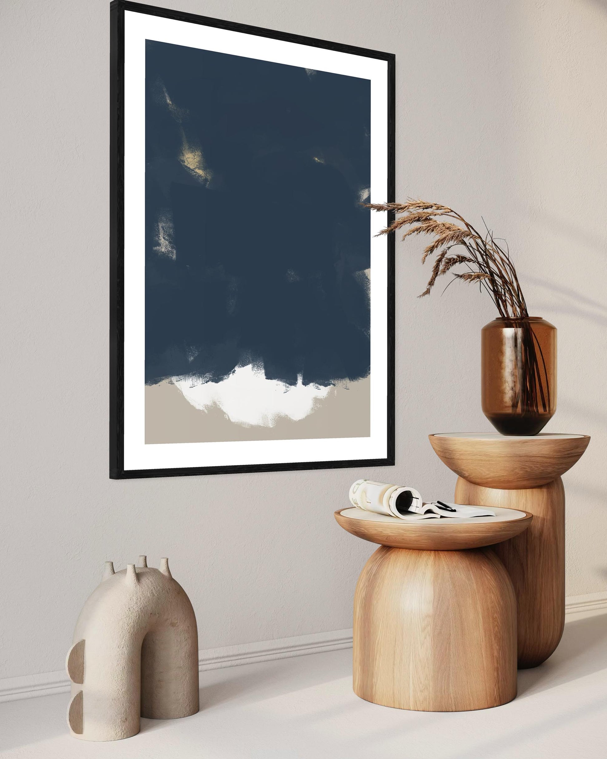 Framed abstract art piece on a wall with wooden stools and decorative items below.