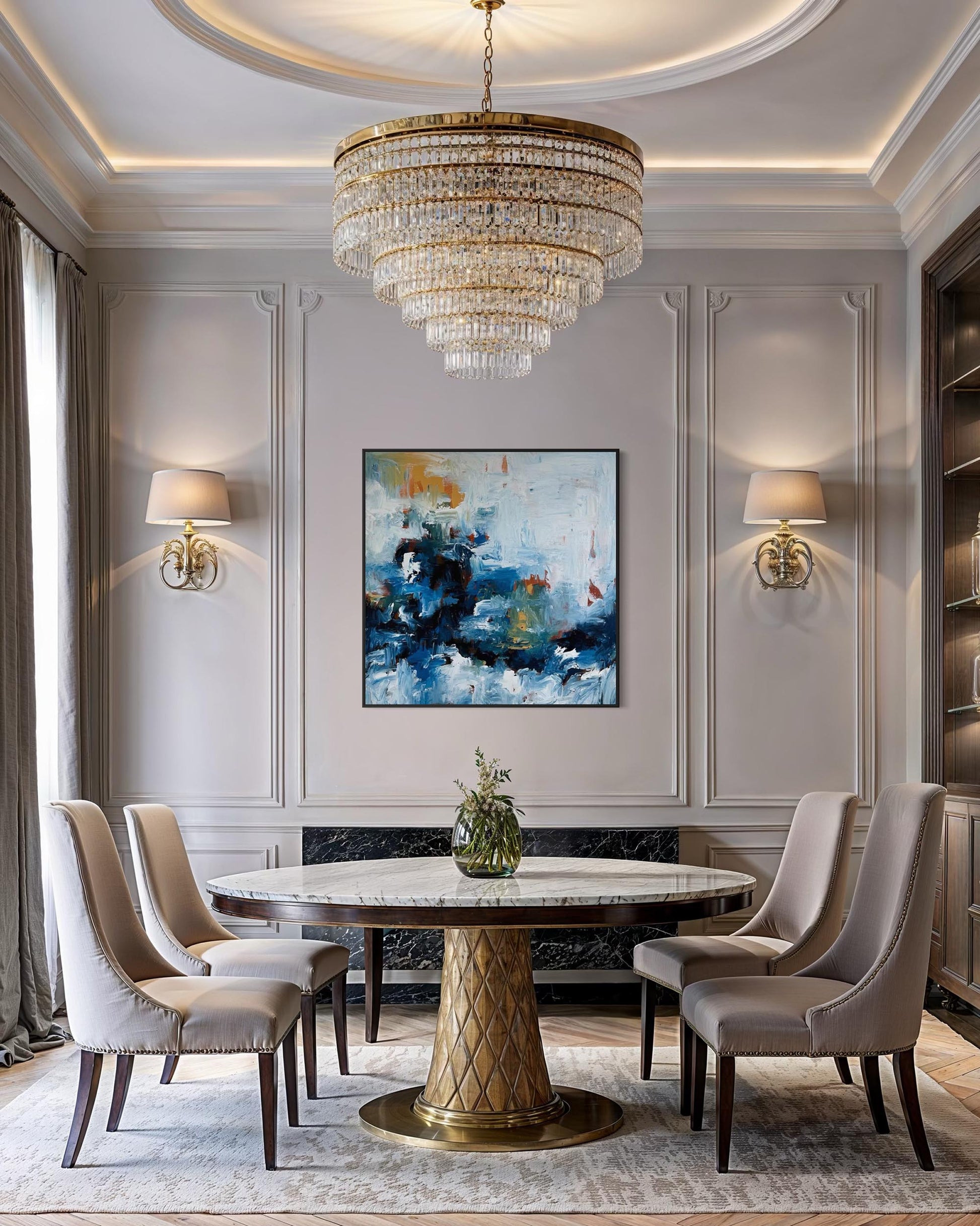 Elegant dining room with a round marble table, gold chandelier, and abstract art on the wall.