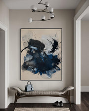 Abstract art piece on a wall in a modern interior setting with a bench and handbag.
