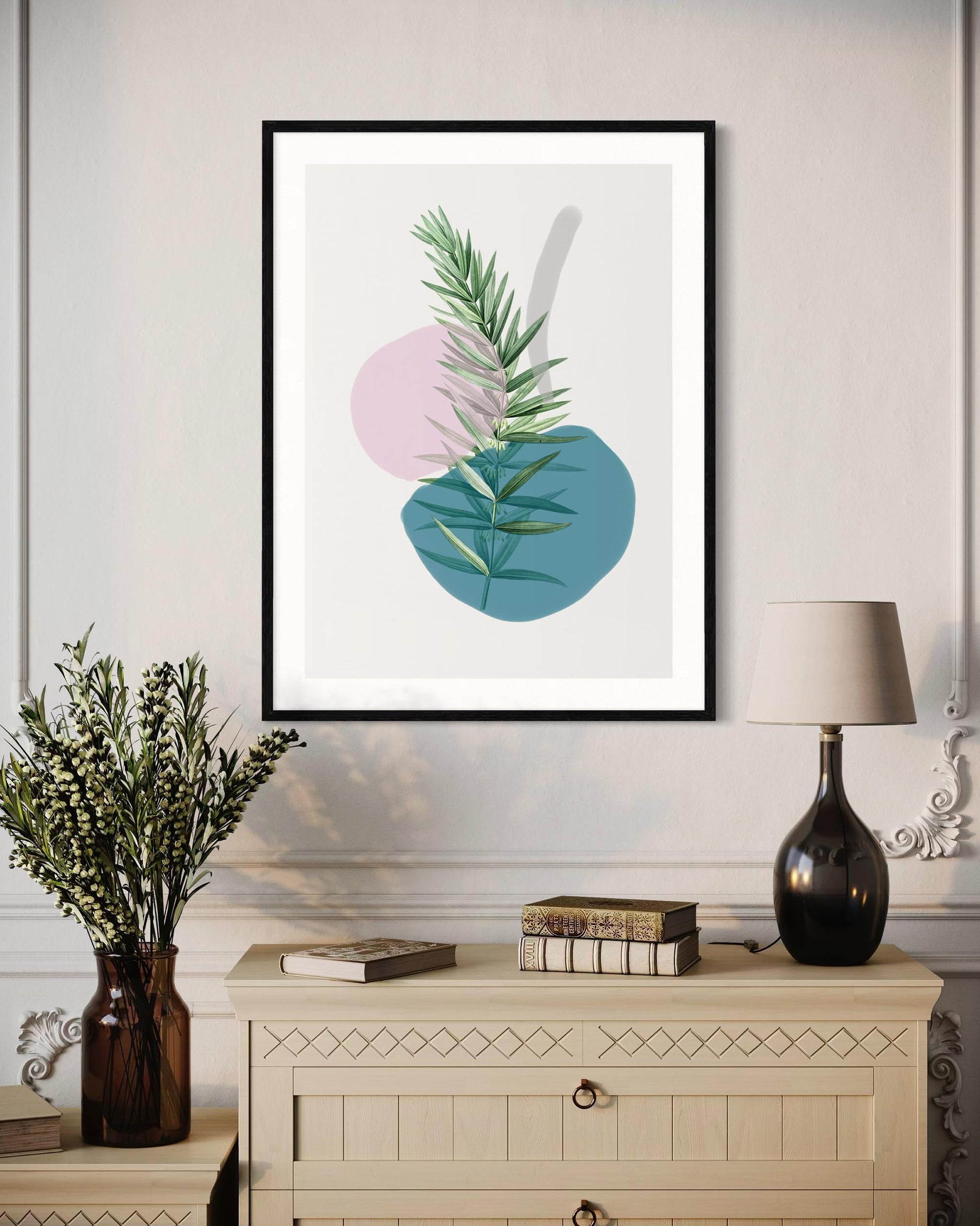 Framed artwork with abstract design of leaves and circles on a wall above a cabinet.
