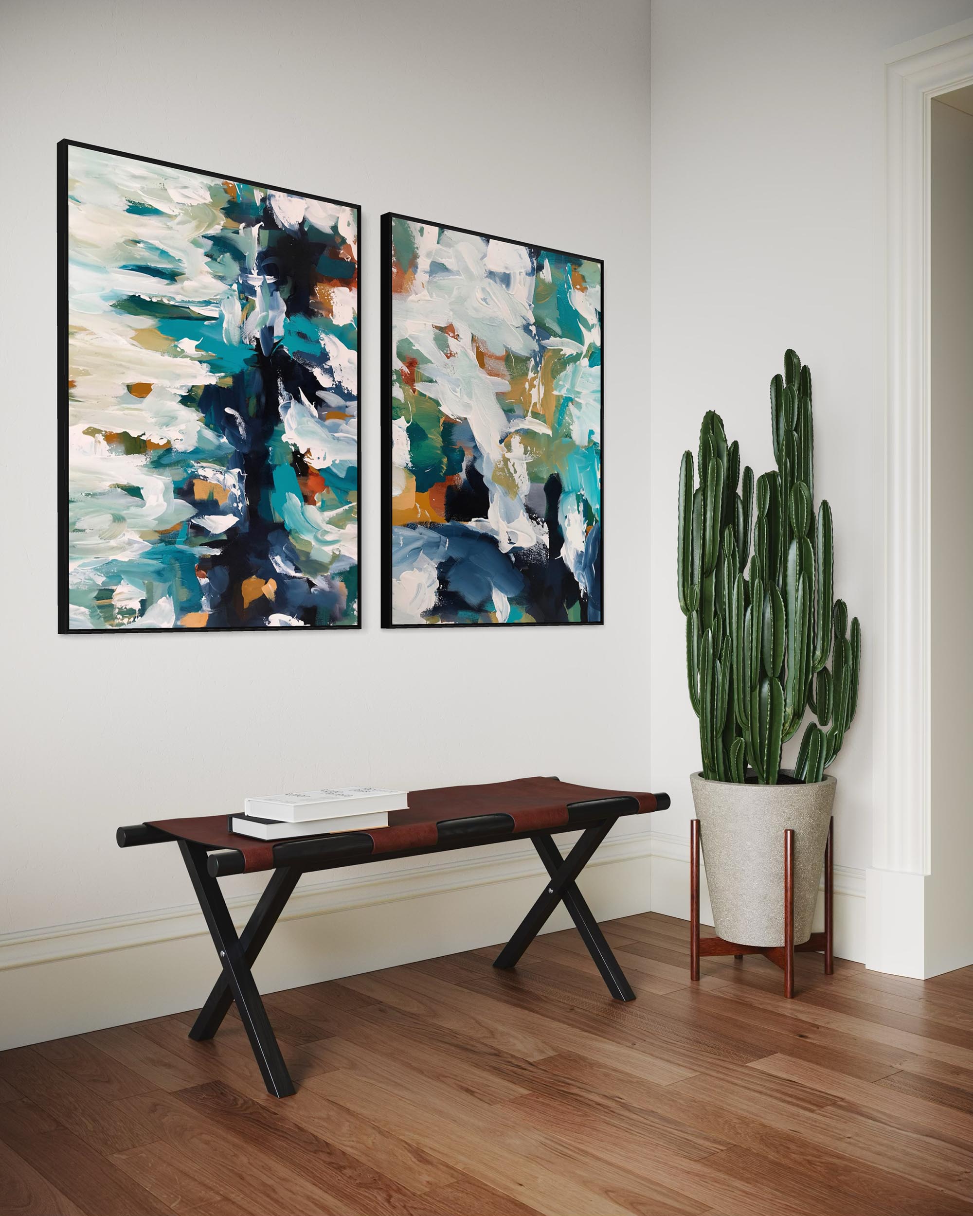 Two abstract paintings on a wall above a wooden bench with a cactus plant in the corner.