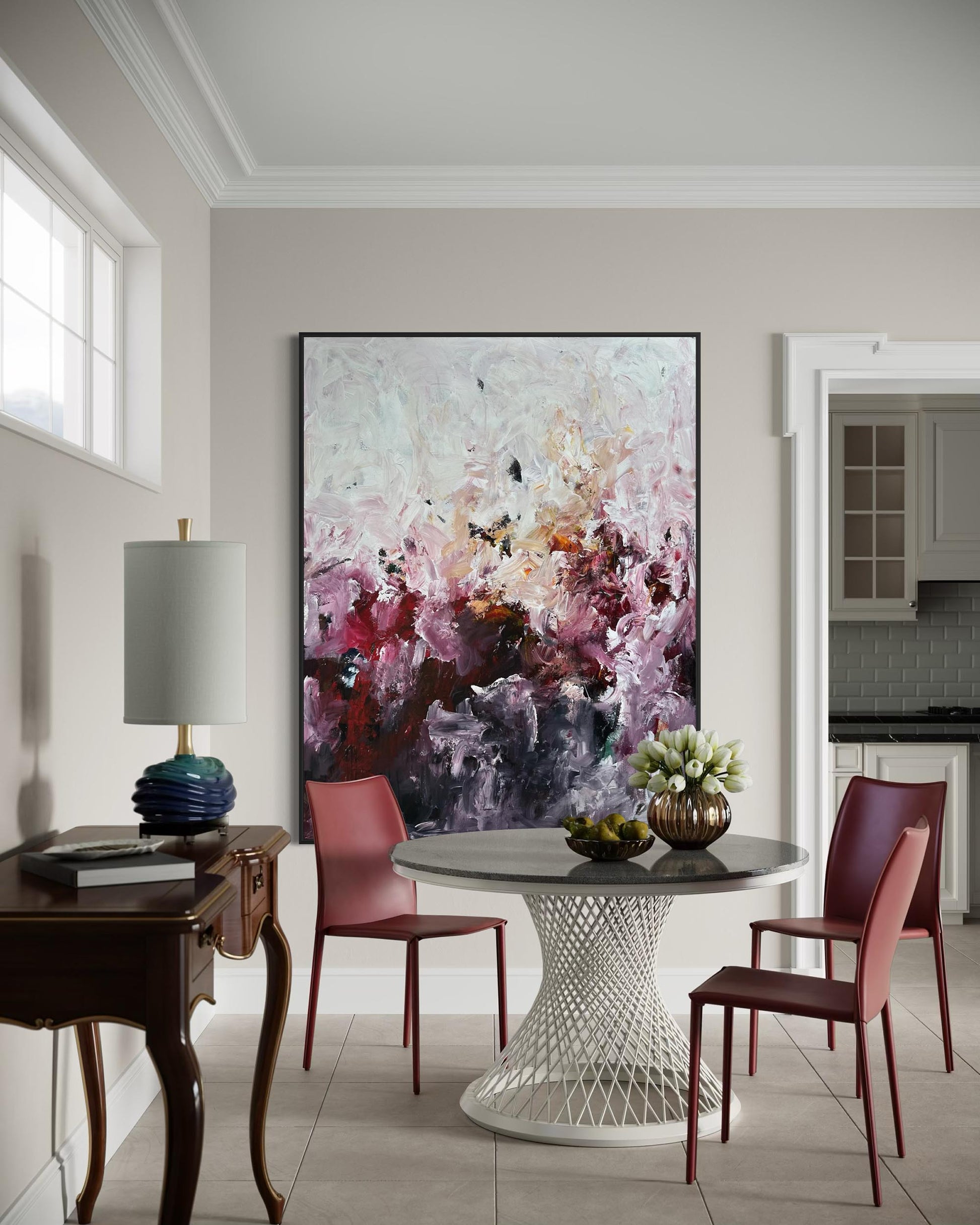 Dining room with a large abstract painting on the wall, round table, and chairs.