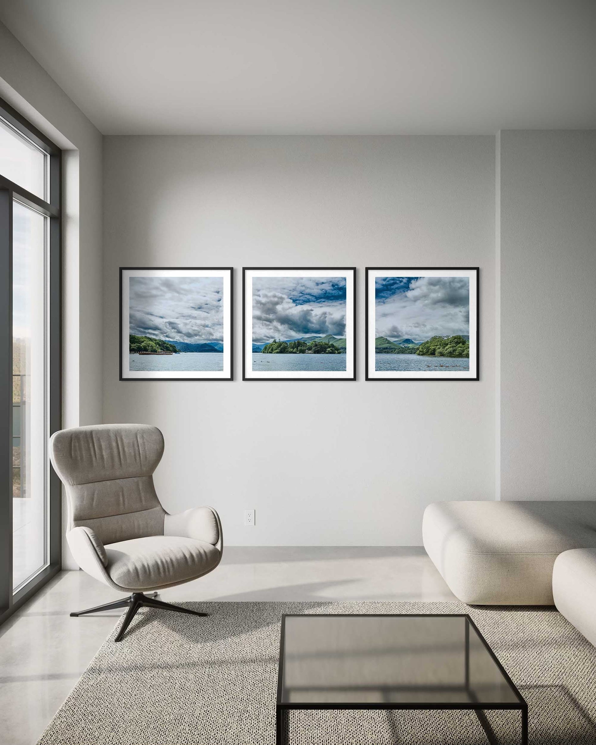 Modern living room with a gray armchair, glass coffee table, and three framed landscape pictures on the wall.