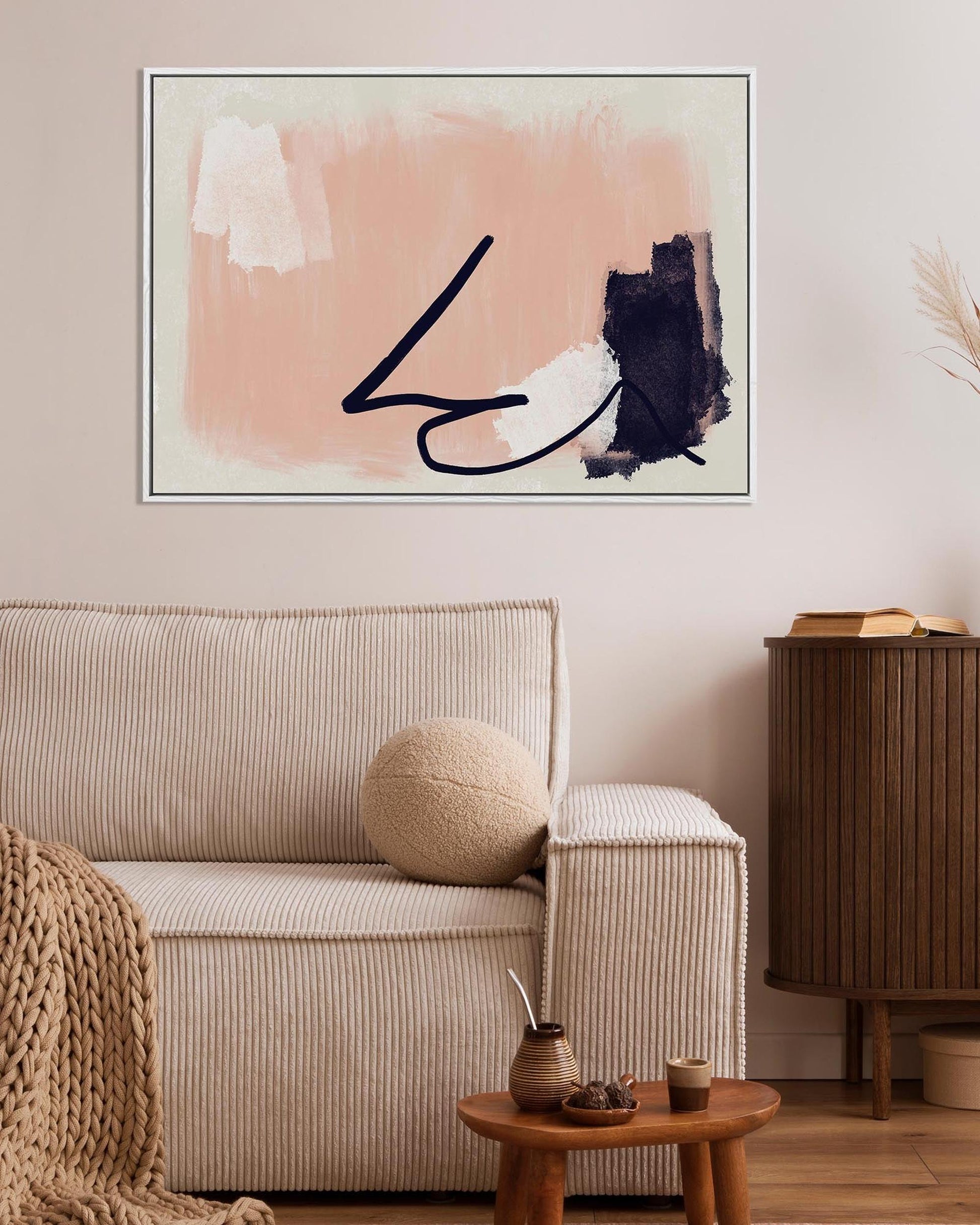 Living room with abstract art on the wall, beige sofa, and wooden side table.