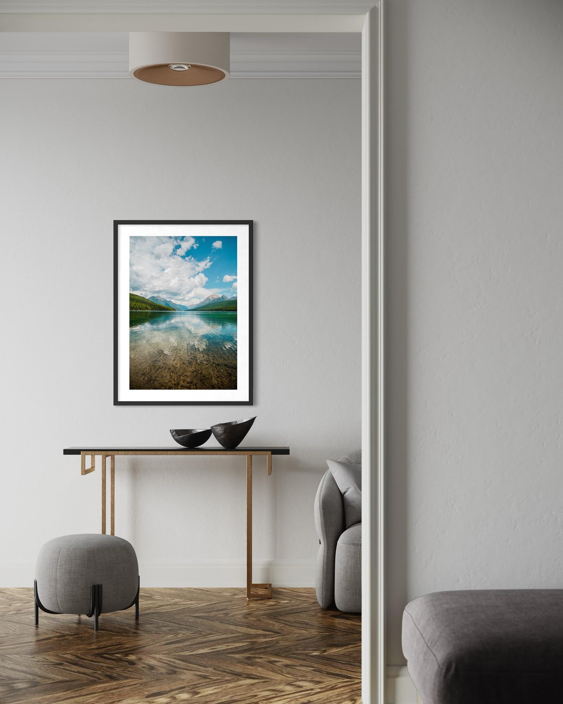 Framed artwork on a wall in a modern living room with a console table and chairs.